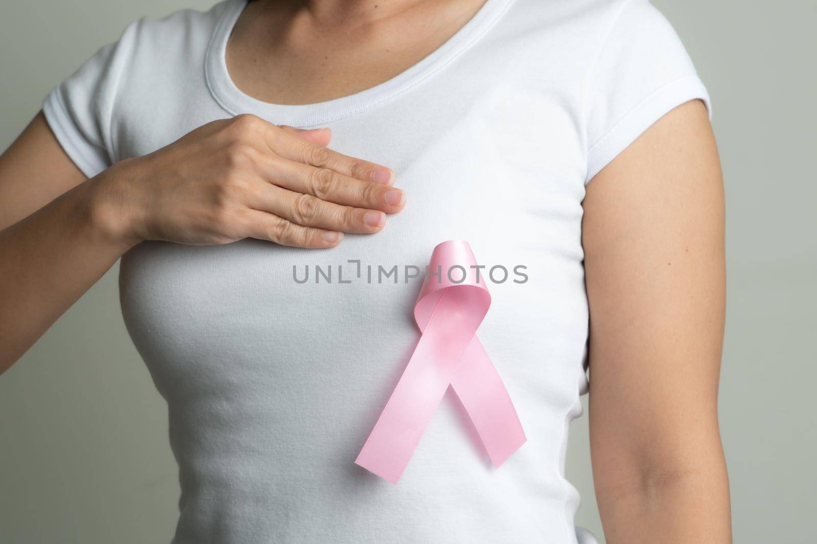 pink badge ribbon on woman chest to support breast cancer cause. breast cancer awareness concept by psodaz