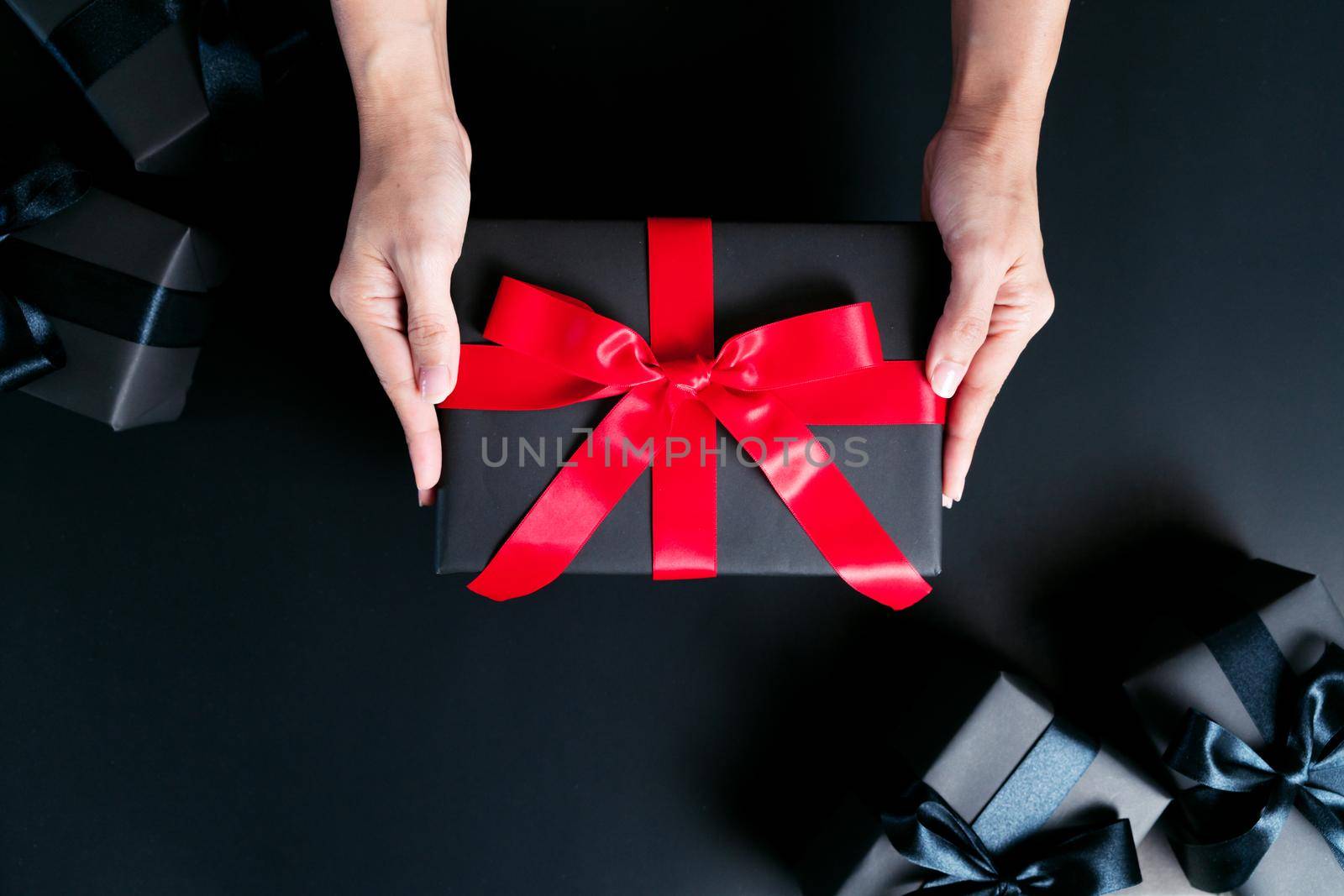 Boxing day Sale concept, woman hand give the gift box on black background