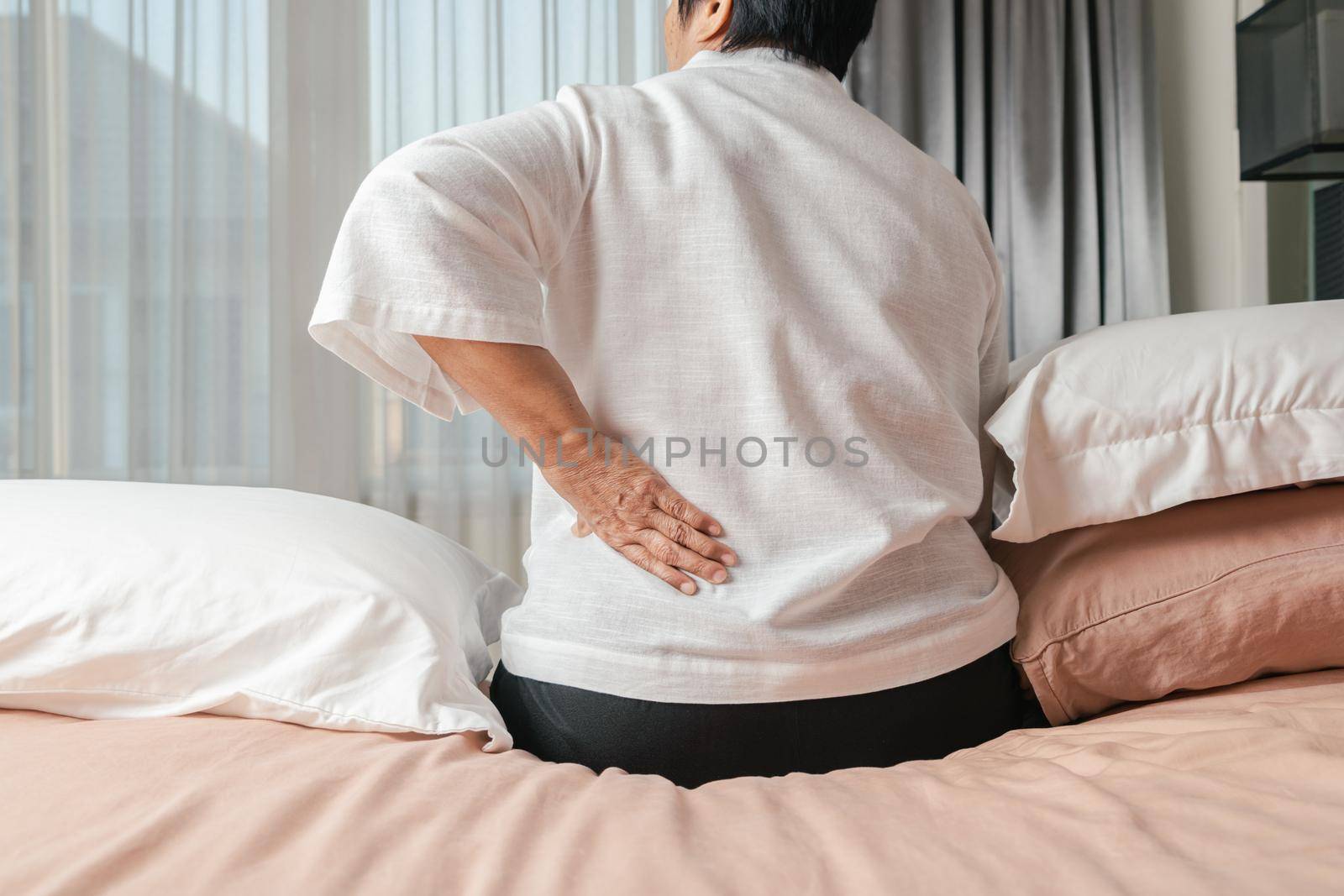Old woman back pain at home, health problem concept by psodaz