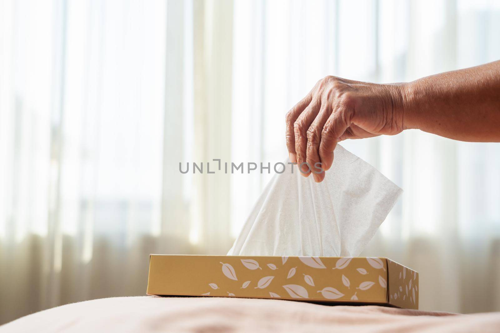 Senior women hand picking napkin/tissue paper from the tissue box by psodaz