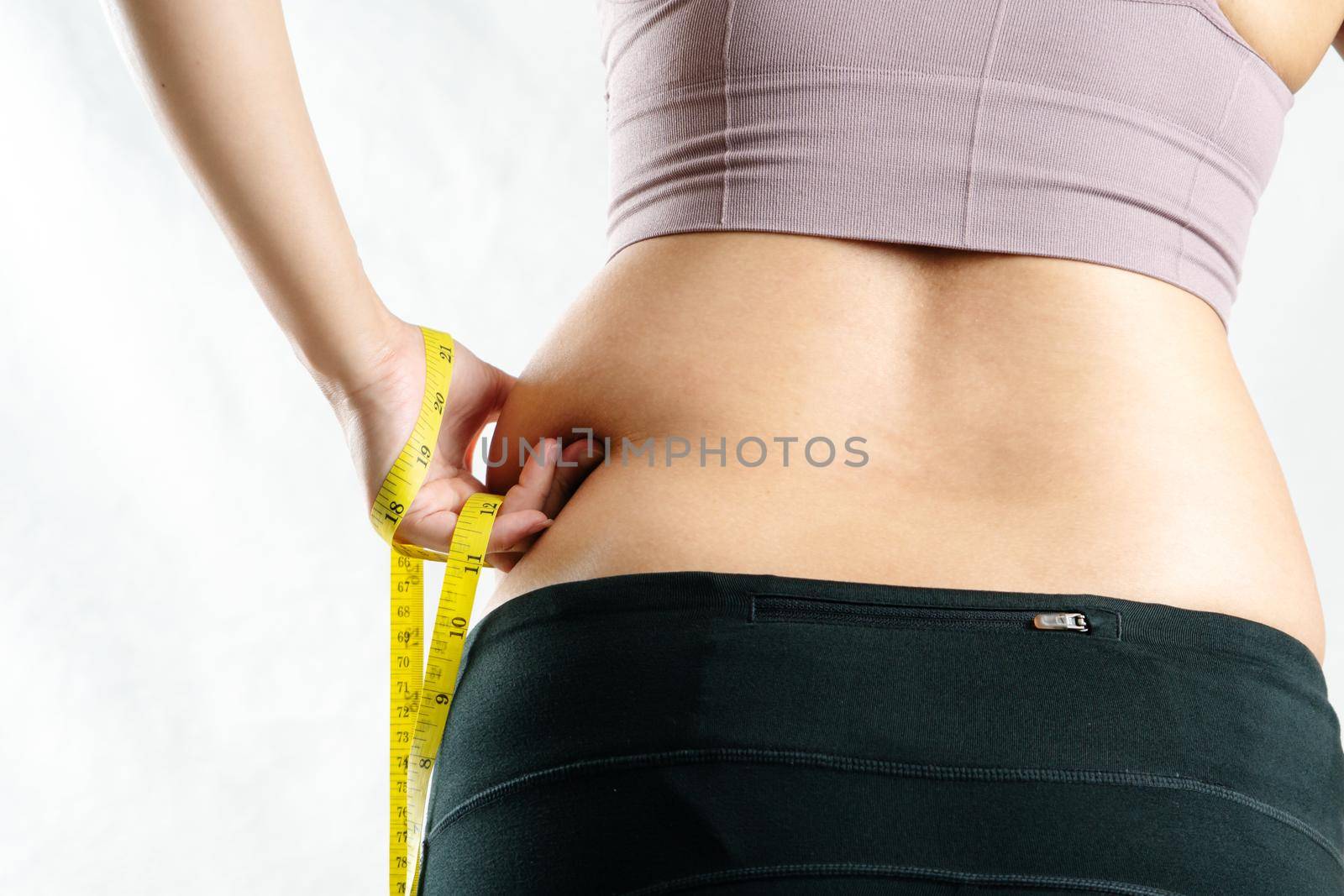 fat woman, fat belly, chubby, obese woman hand pinching on her excessive belly fat waist with measure tape, woman diet lifestyle concept - rear view by psodaz