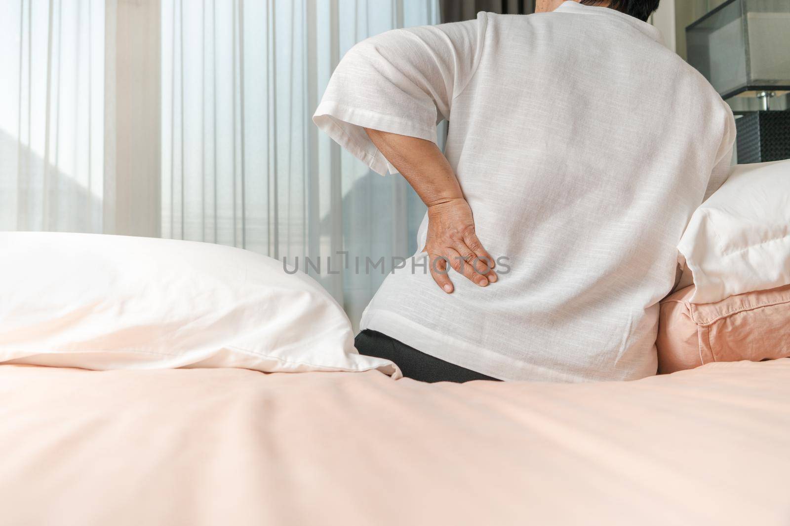 Old woman back pain at home, health problem concept by psodaz