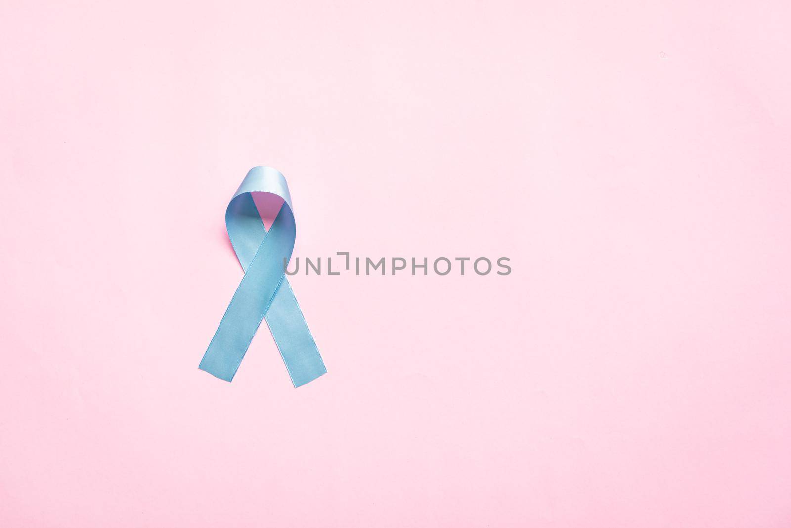 November light blue ribbon on pink background with copy space, Prostate cancer awareness month, men's health concept