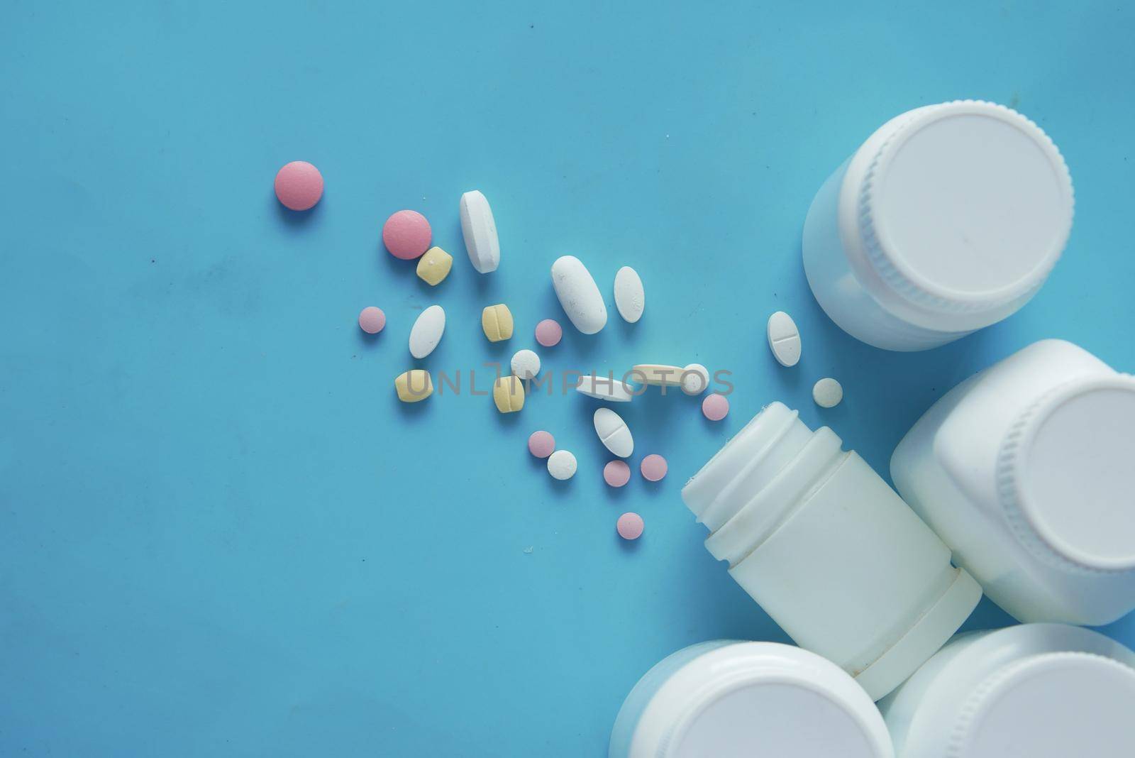 white color medical pills spilling on blue background ,