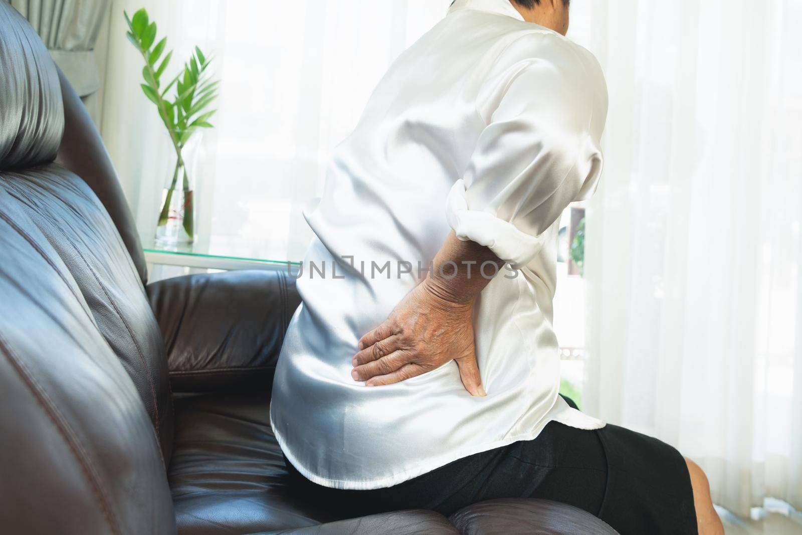 Old woman back pain at home, health problem concept by psodaz
