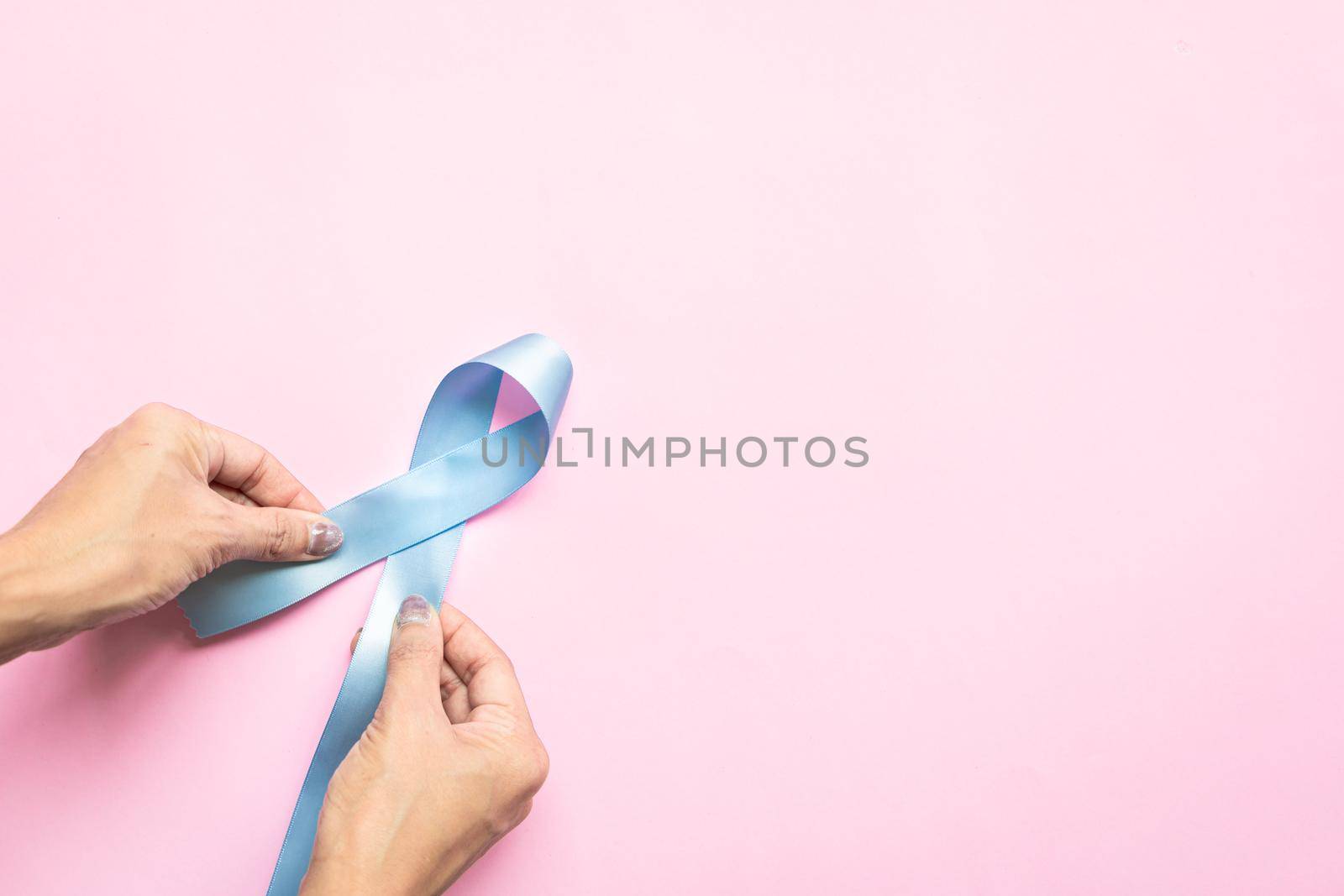 November light blue ribbon on woman hand with copy space, Prostate cancer awareness month, men's health concept by psodaz