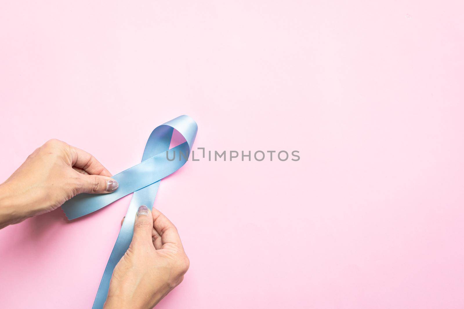 November light blue ribbon on woman hand with copy space, Prostate cancer awareness month, men's health concept