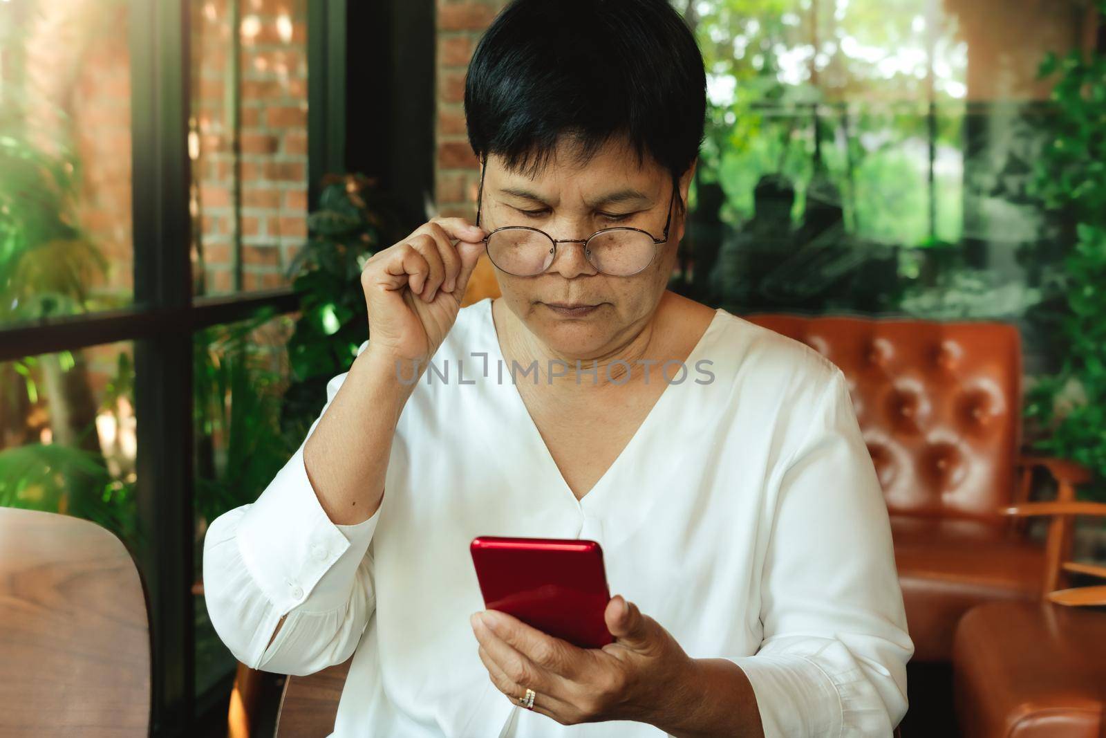 Senior woman wearing  glasses and lookning at smartphone