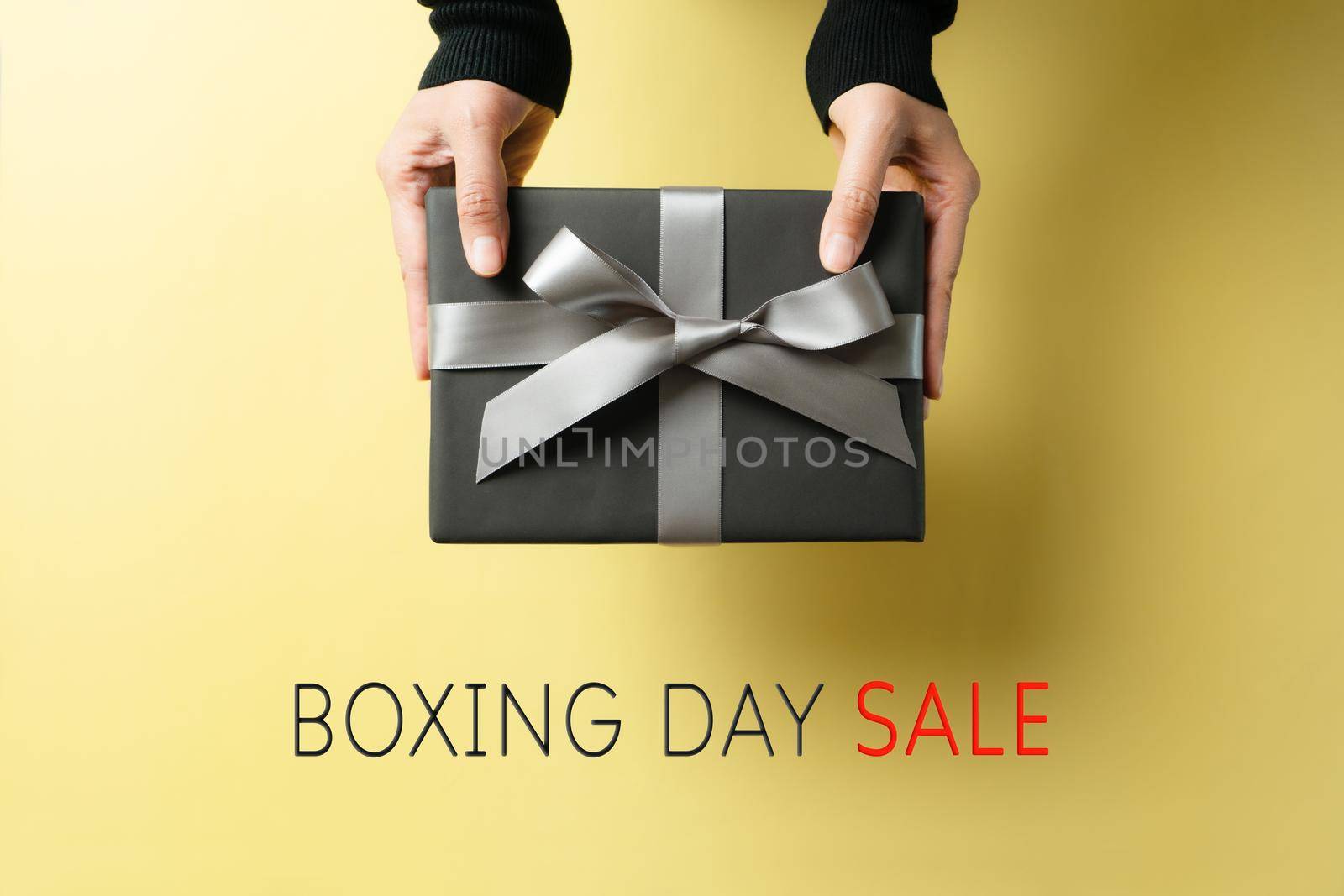 Boxing Day sale, young woman hand with a gift box offer to receiver by psodaz