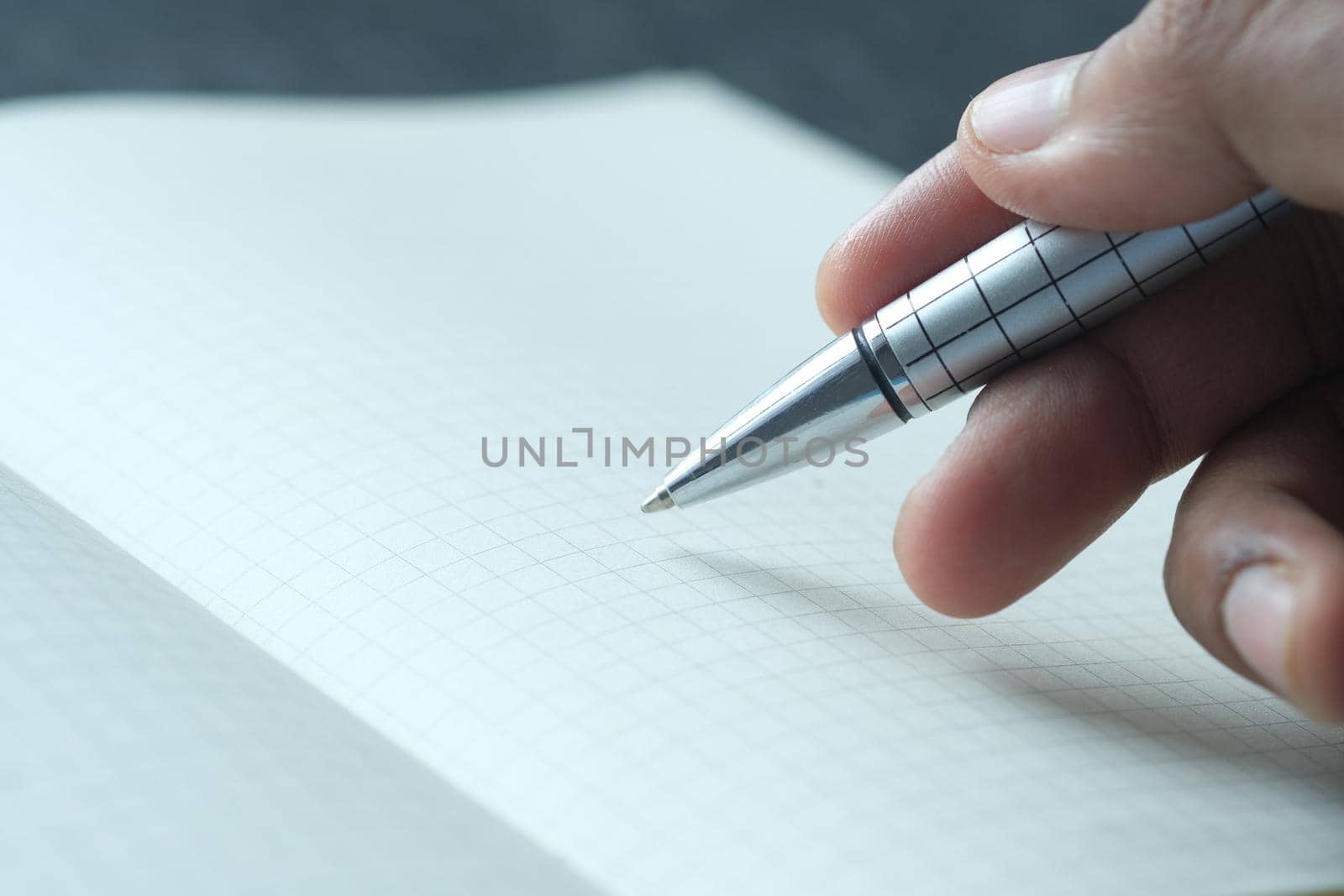man's hand writing with pen on paper.