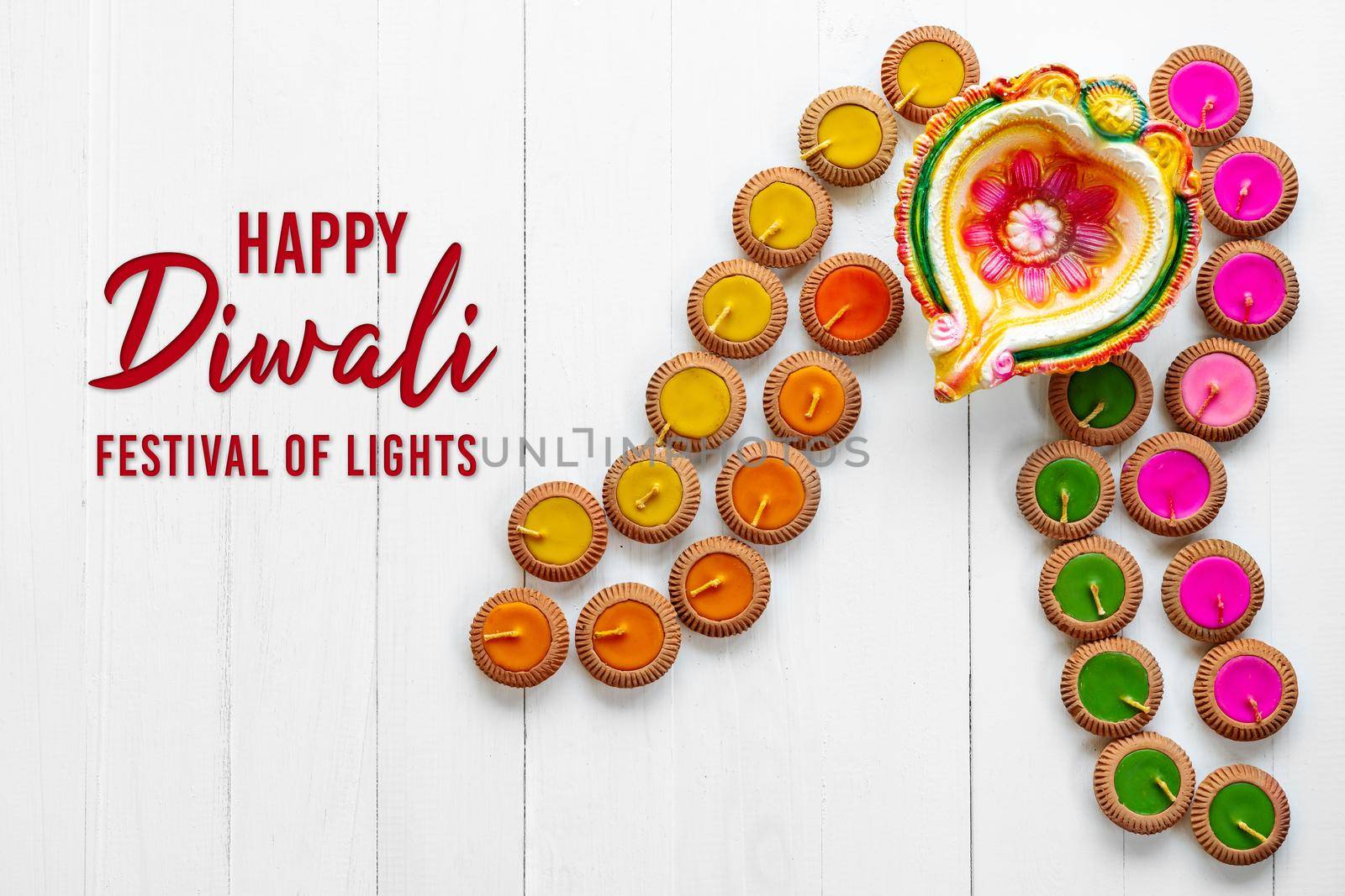 Happy Diwali - Clay Diya lamps lit during Dipavali, Hindu festival of lights celebration. Colorful traditional oil lamp diya on white wooden background