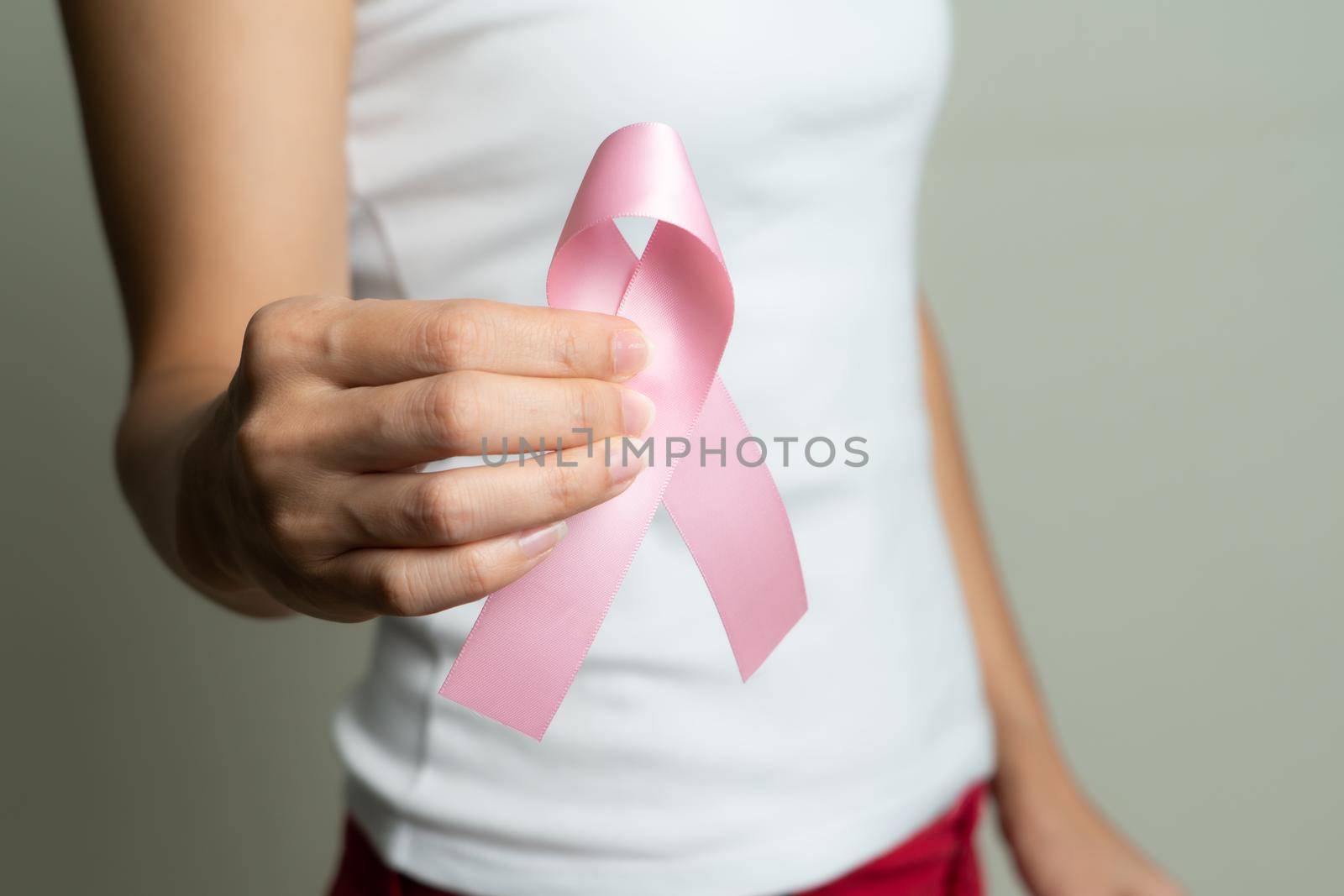 Woman hand holding pink ribbon breast cancer awareness.