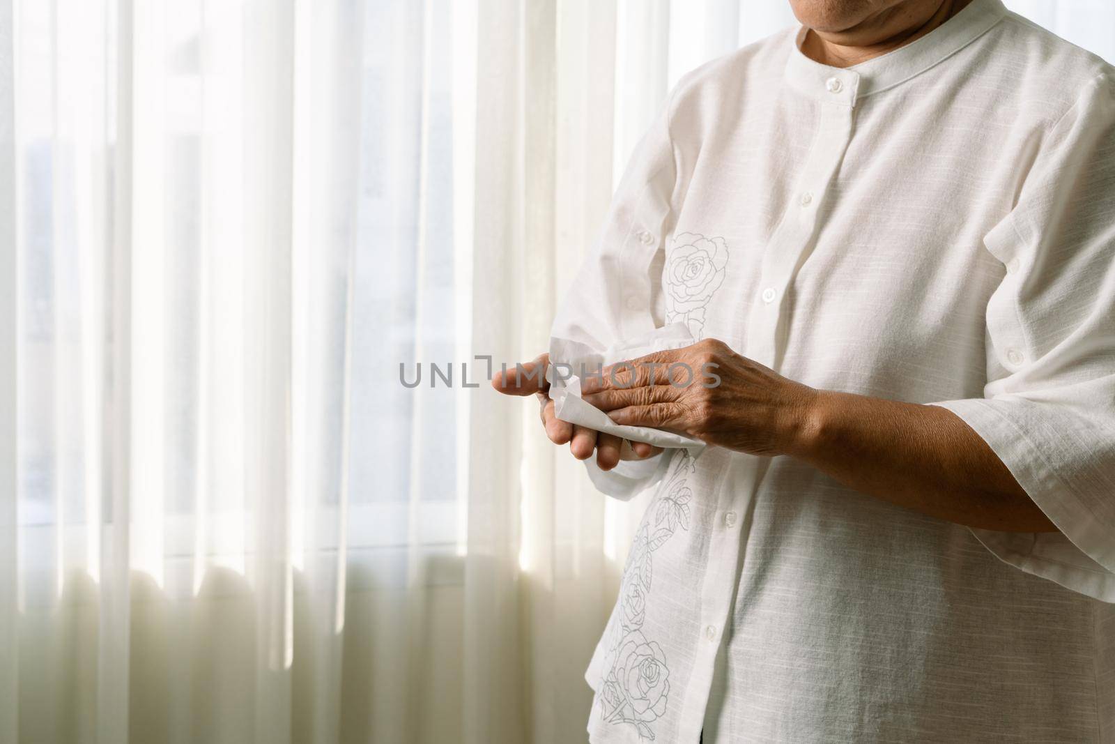 Senior woman cleaning her hands with white soft tissue paper. isolated on a white backgrounds by psodaz