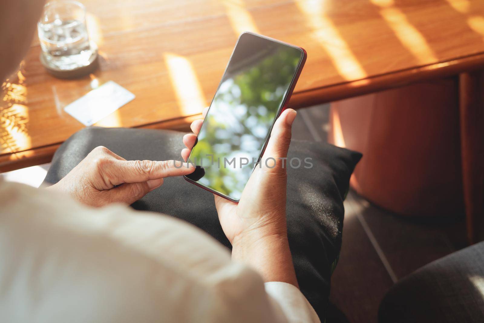 senior lady sitting in a chair and touching the screen of smartphone, online shopping concept
