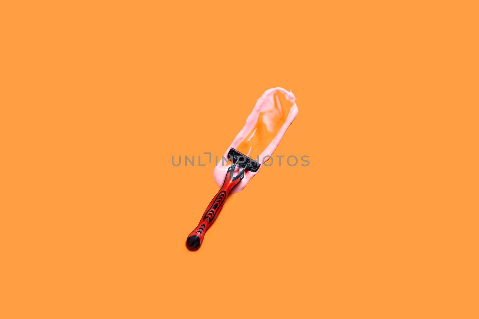 Shaving foam gel and razor on orange background. A multiple use shaving razor and cream. View from above