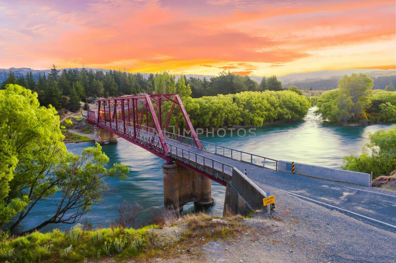Beautiful sunset over the Clyde bridge on the river Clutha with Southern Alps peaks on the horizon, New Zealand