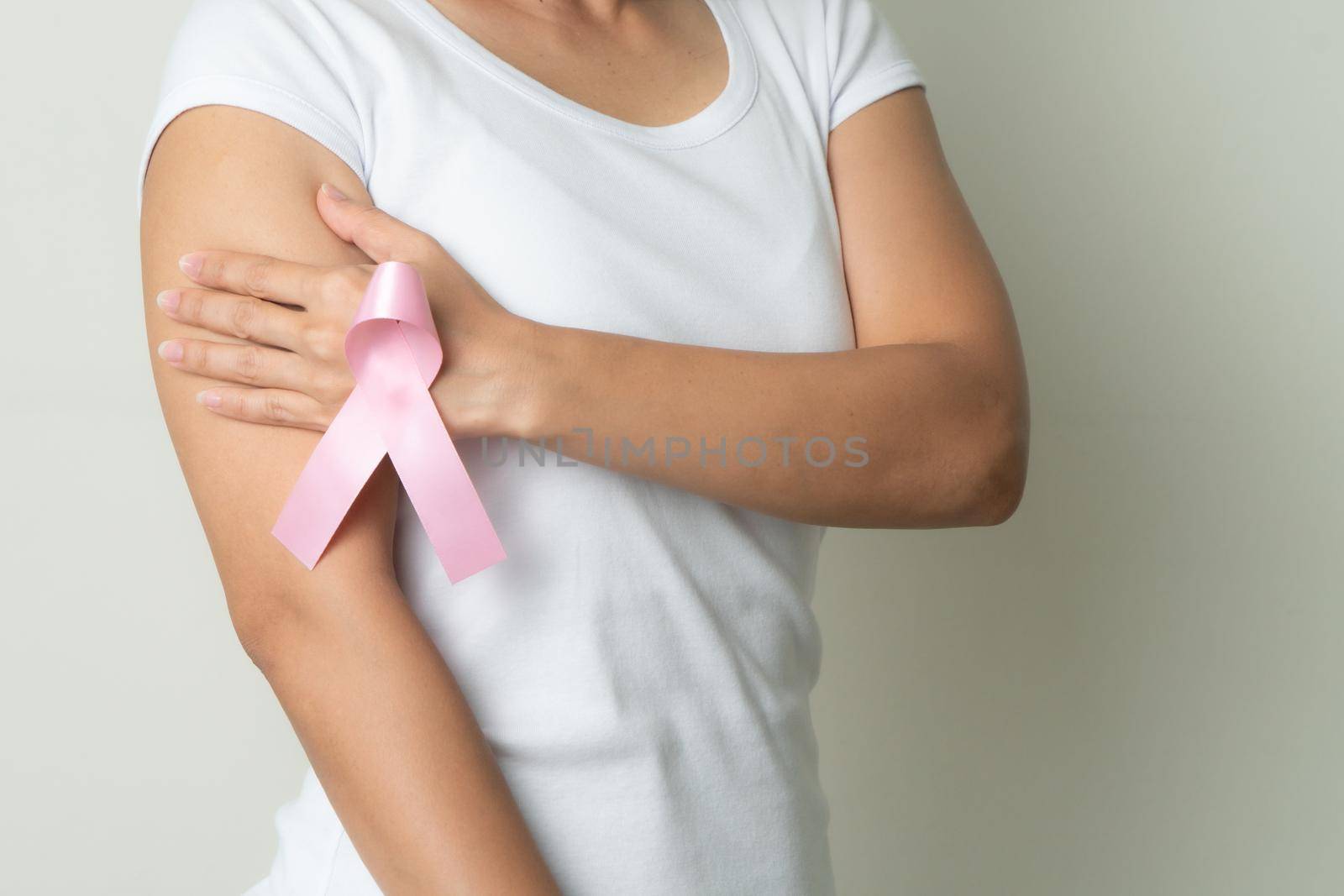 pink badge ribbon on woman hand touching chest to support breast cancer cause. breast cancer awareness concept by psodaz