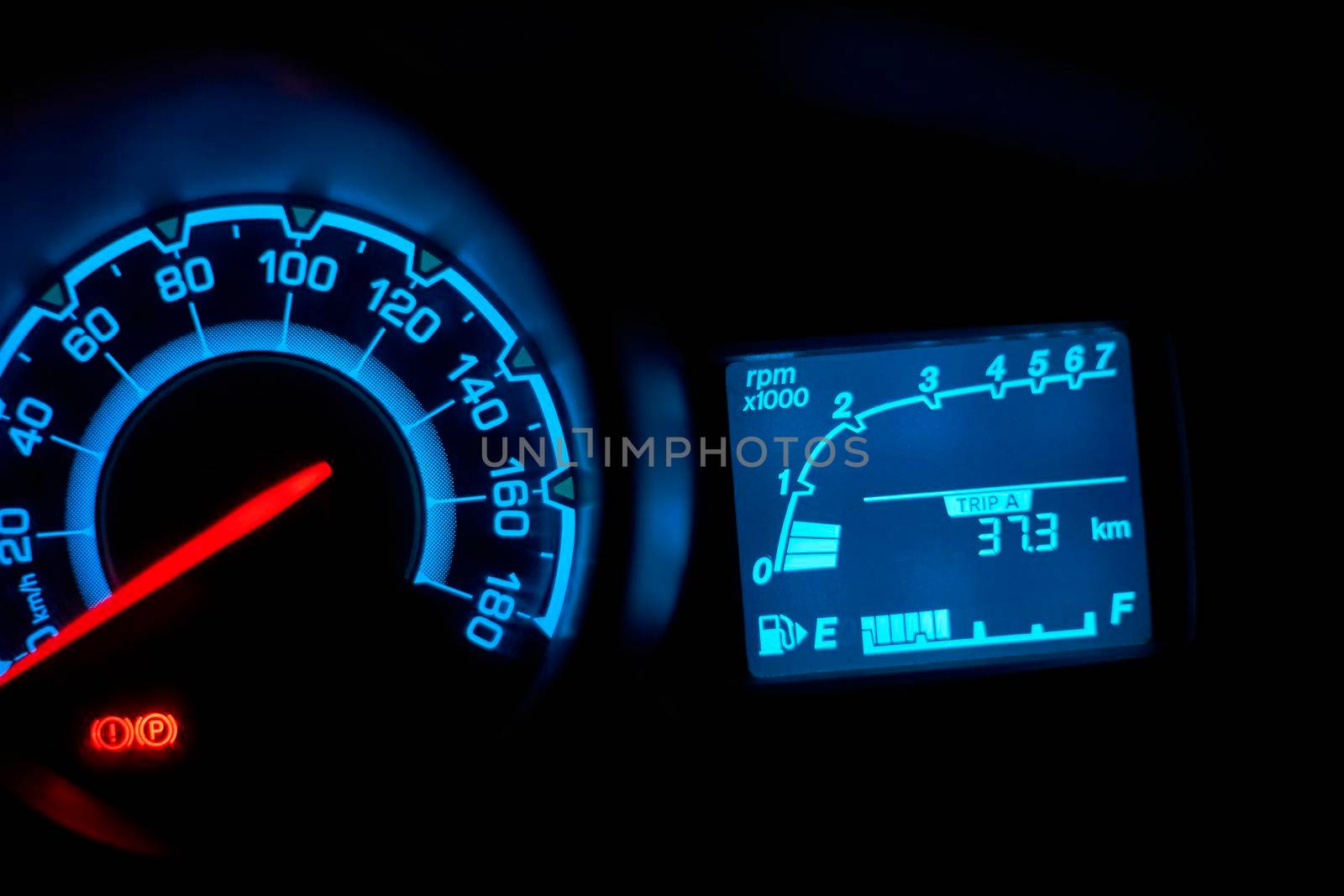Automobile dashboard in neon light at night. Neon light in blue of car milage and speed panel during parking and many of safety icon and car status signal appearance