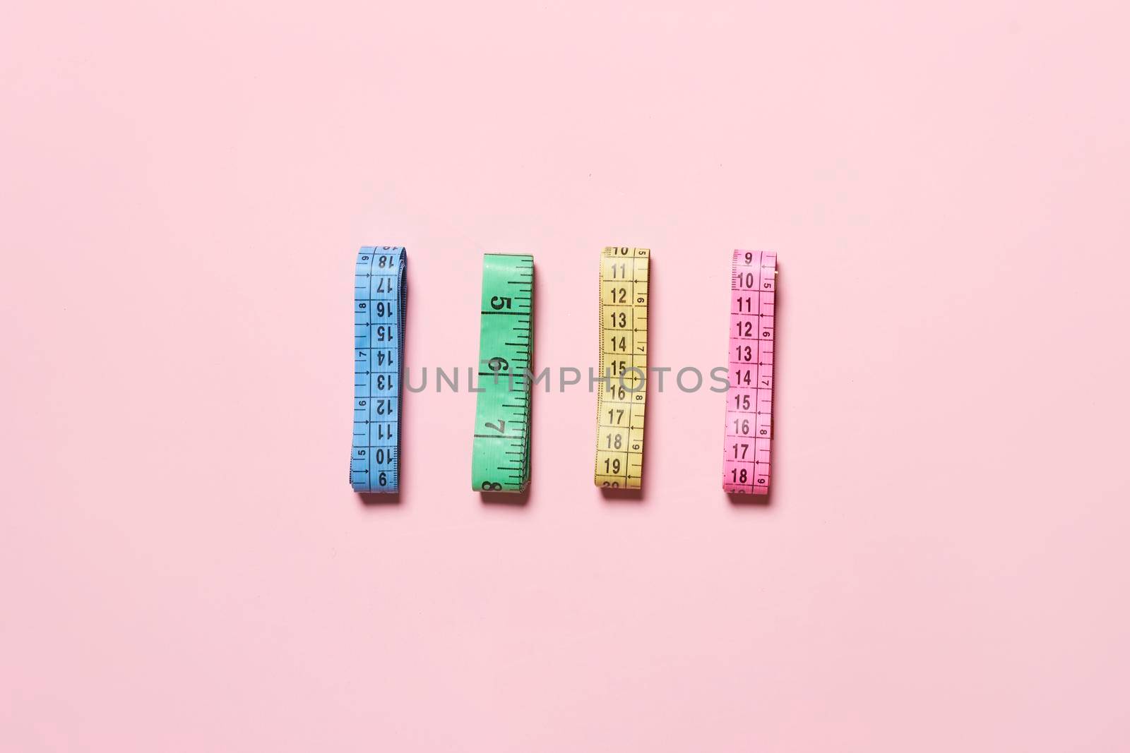Collection of colorful measuring tapes on bright background.