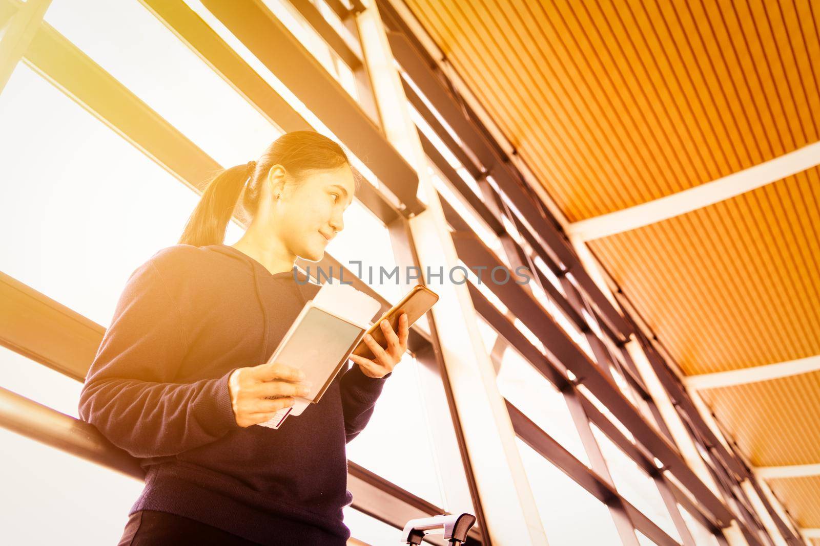 Asia woman using mobile phone while waiting flight in modern terminal by psodaz