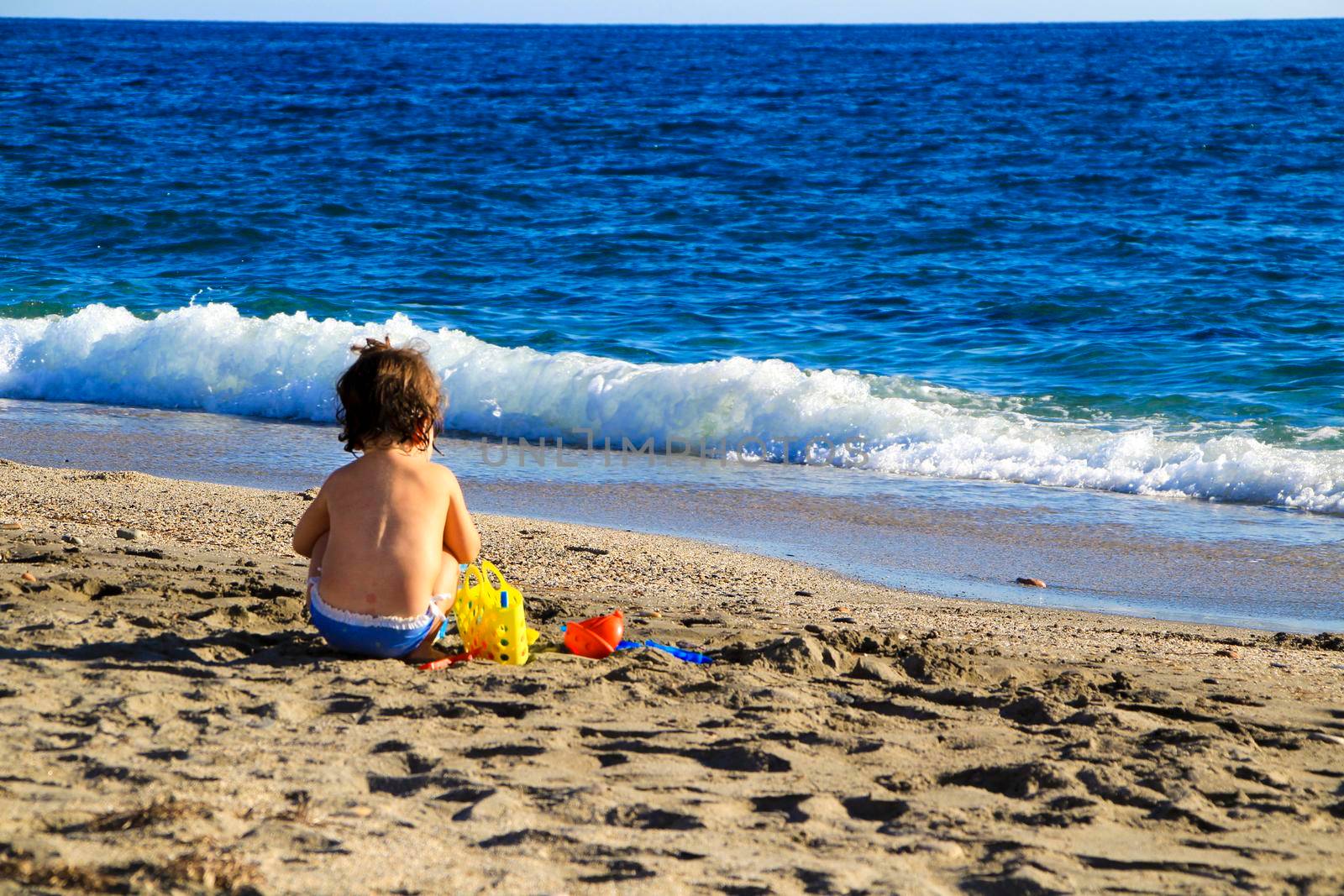 Baby playing on the sand of the Salinas beach in Cabo de Gata, Almeria, Spain