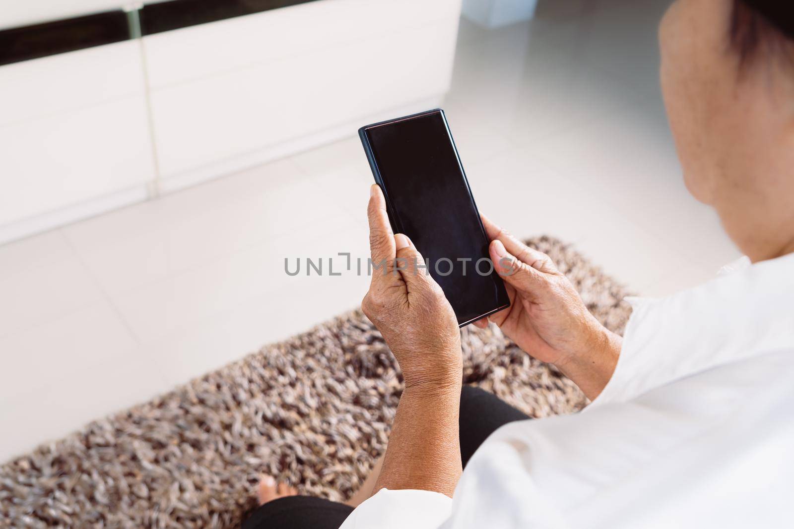 senior woman using mobile phone while sitting on sofa at home