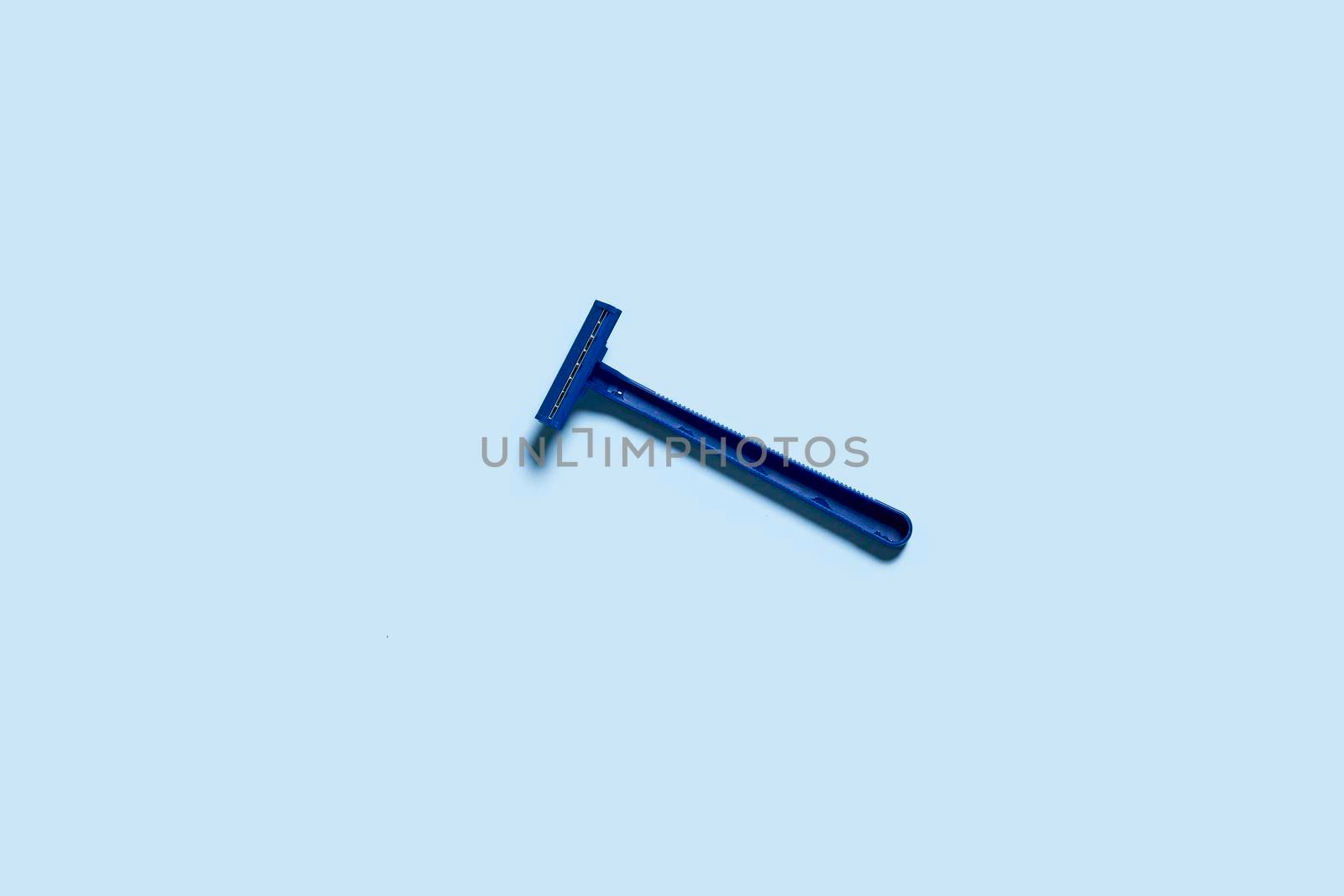 A single use shaving razor on blue background. View from above