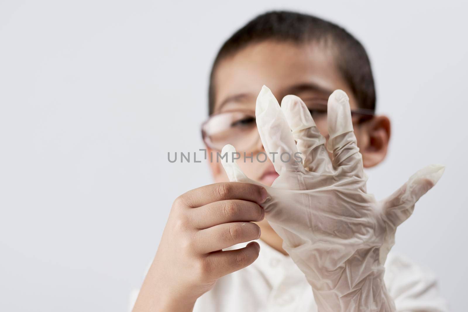 Little scientist kid wearing protective glove before his chemistry experiments with liquids