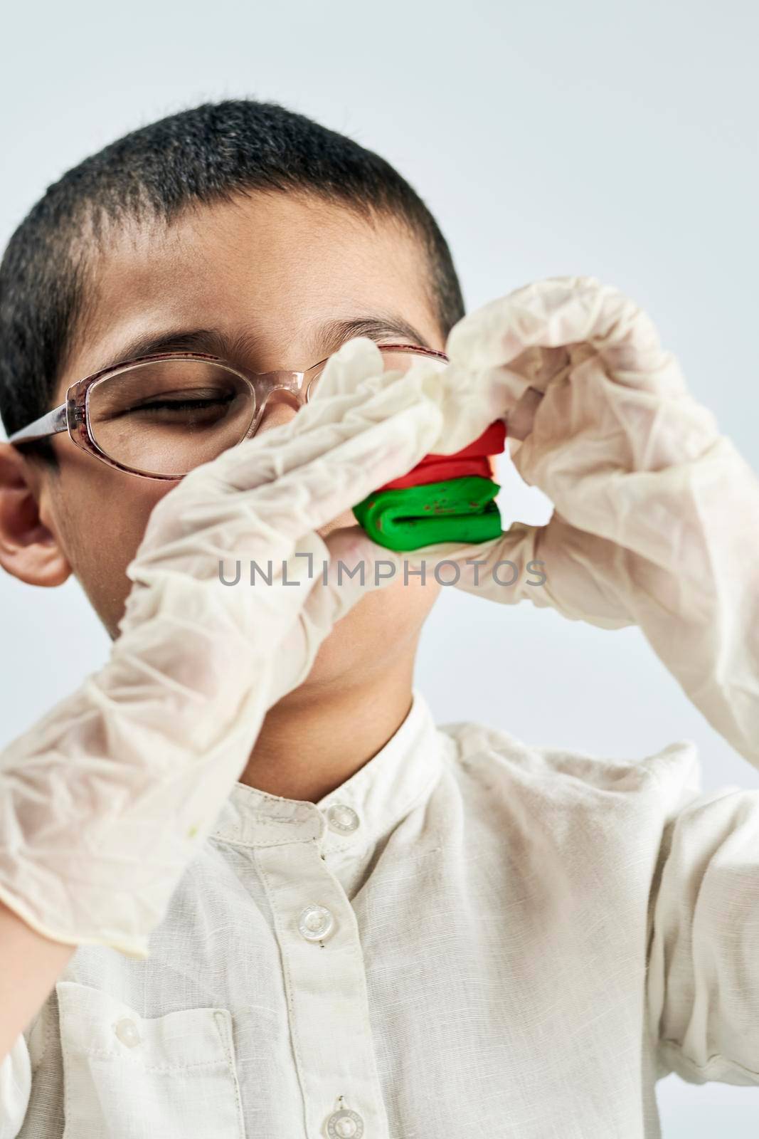 A kid in glasses and gloves playing with plasticine by golibtolibov