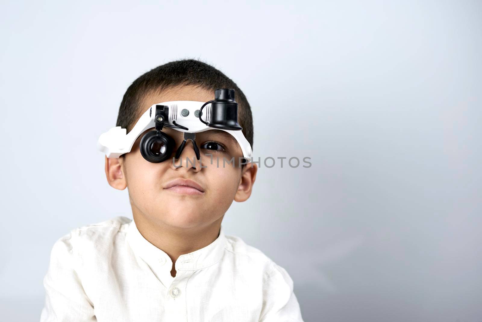 Boy looking through magnifying eyeglasses by golibtolibov