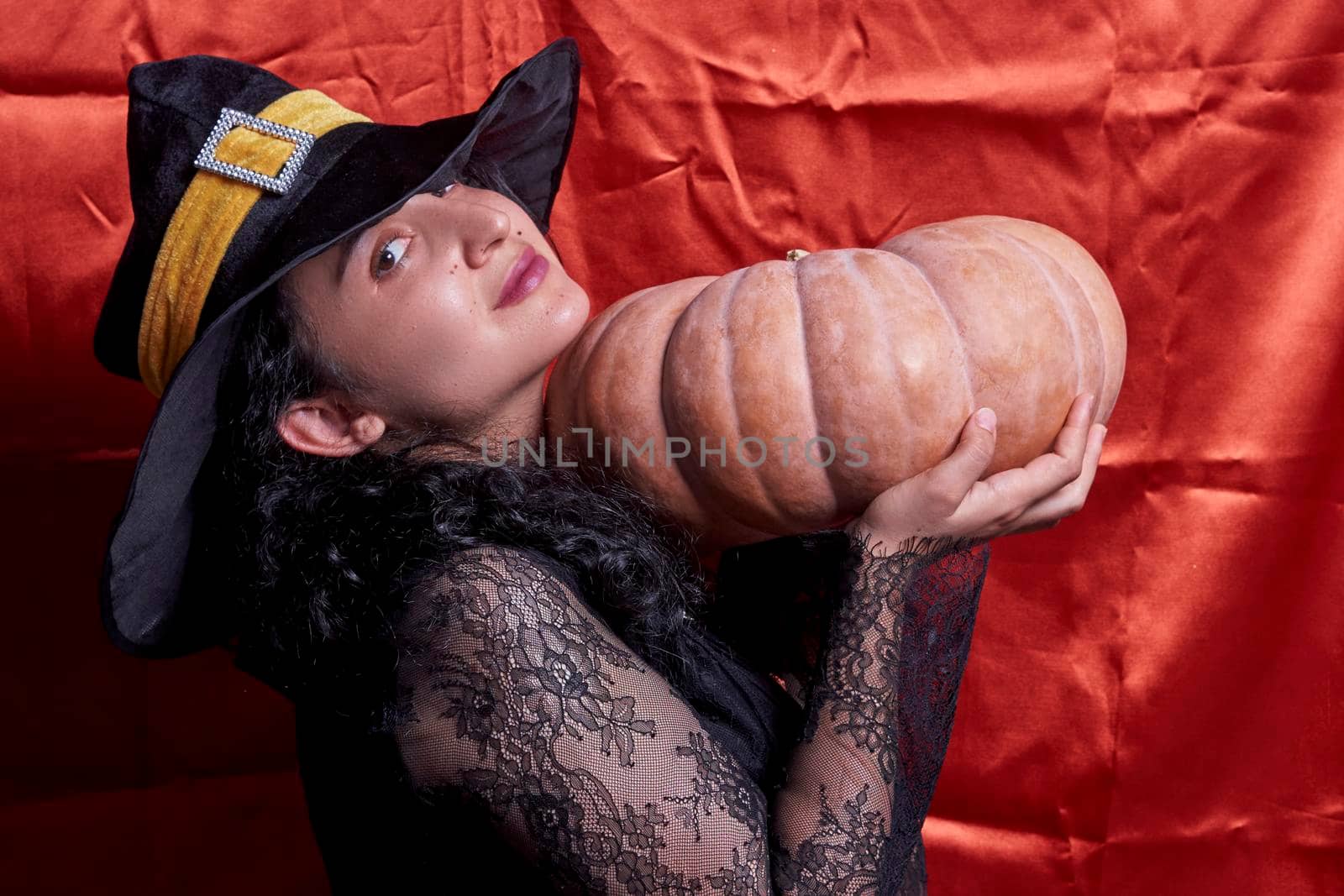 Halloween lady wearing witch cup and holding a big halloween pumpkin by golibtolibov