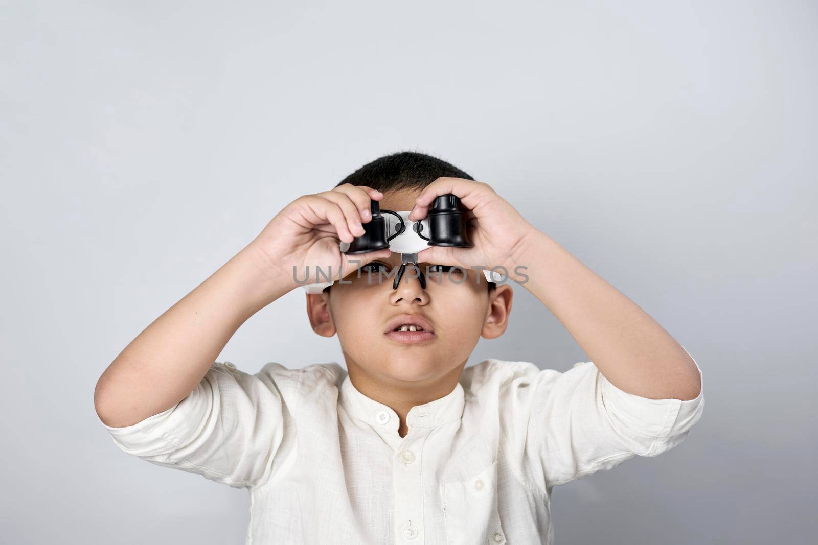 Funny portrait of young cute scientist kid wearing special magnifying eyeglass equipment