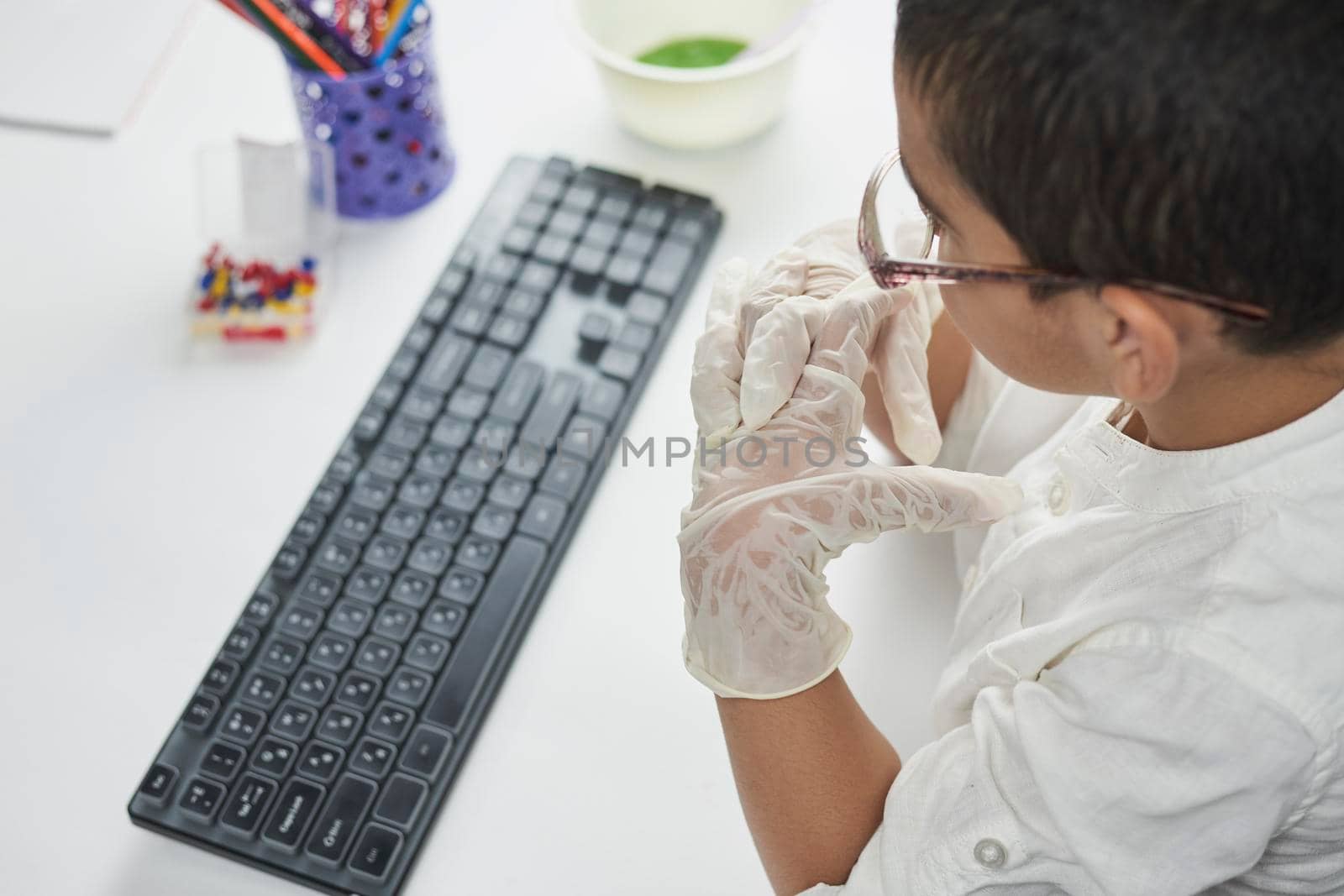 Overhead view of schoolboy typing on keyboard by golibtolibov