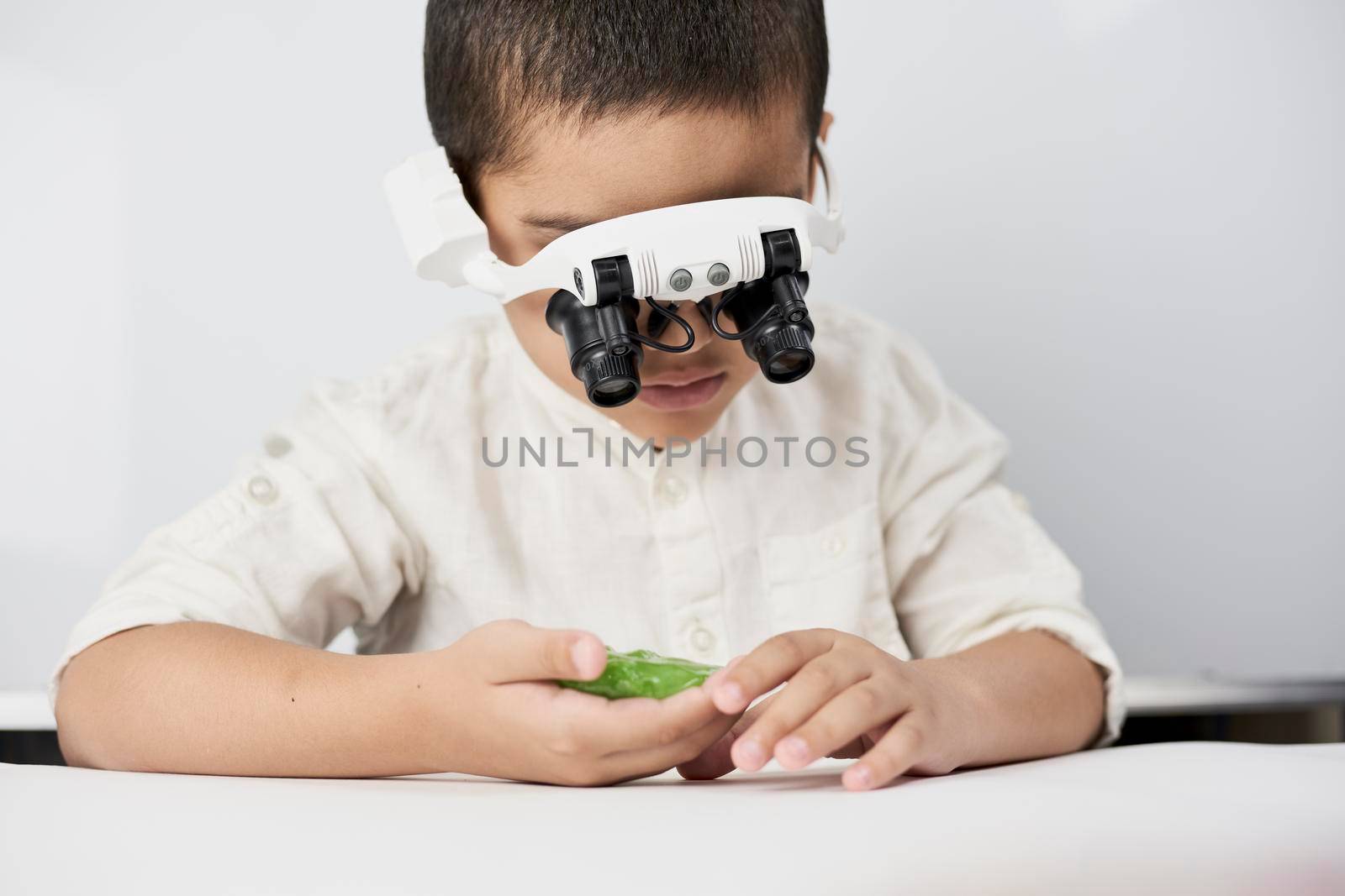 A little boy exploring slime structure with head magnifying glasses headset