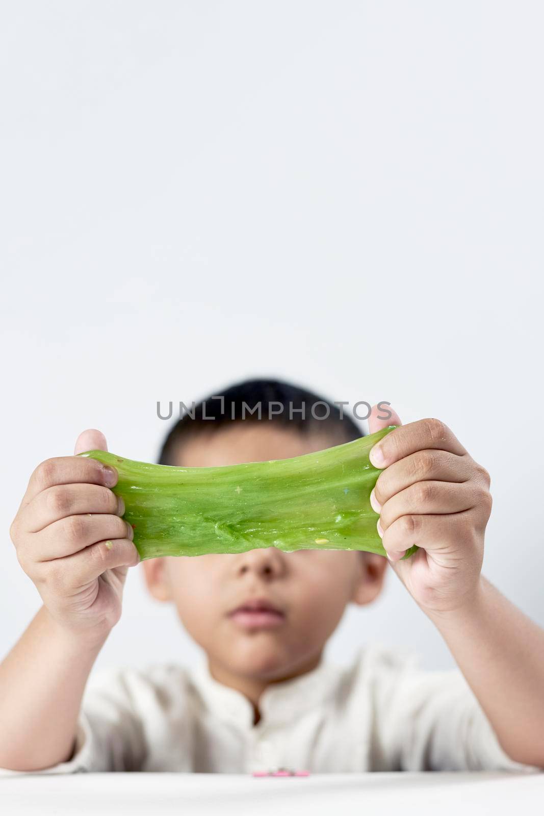 Vertical shot of a kid who loves playing with slime
