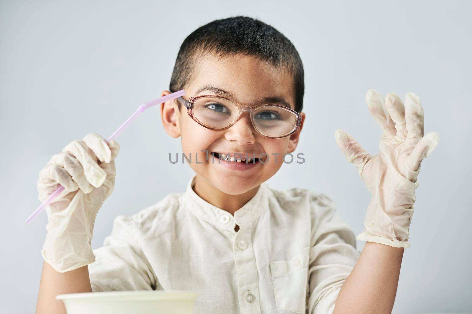 Portrait of 7 years old boy in glasses making funny facial expression against the white background