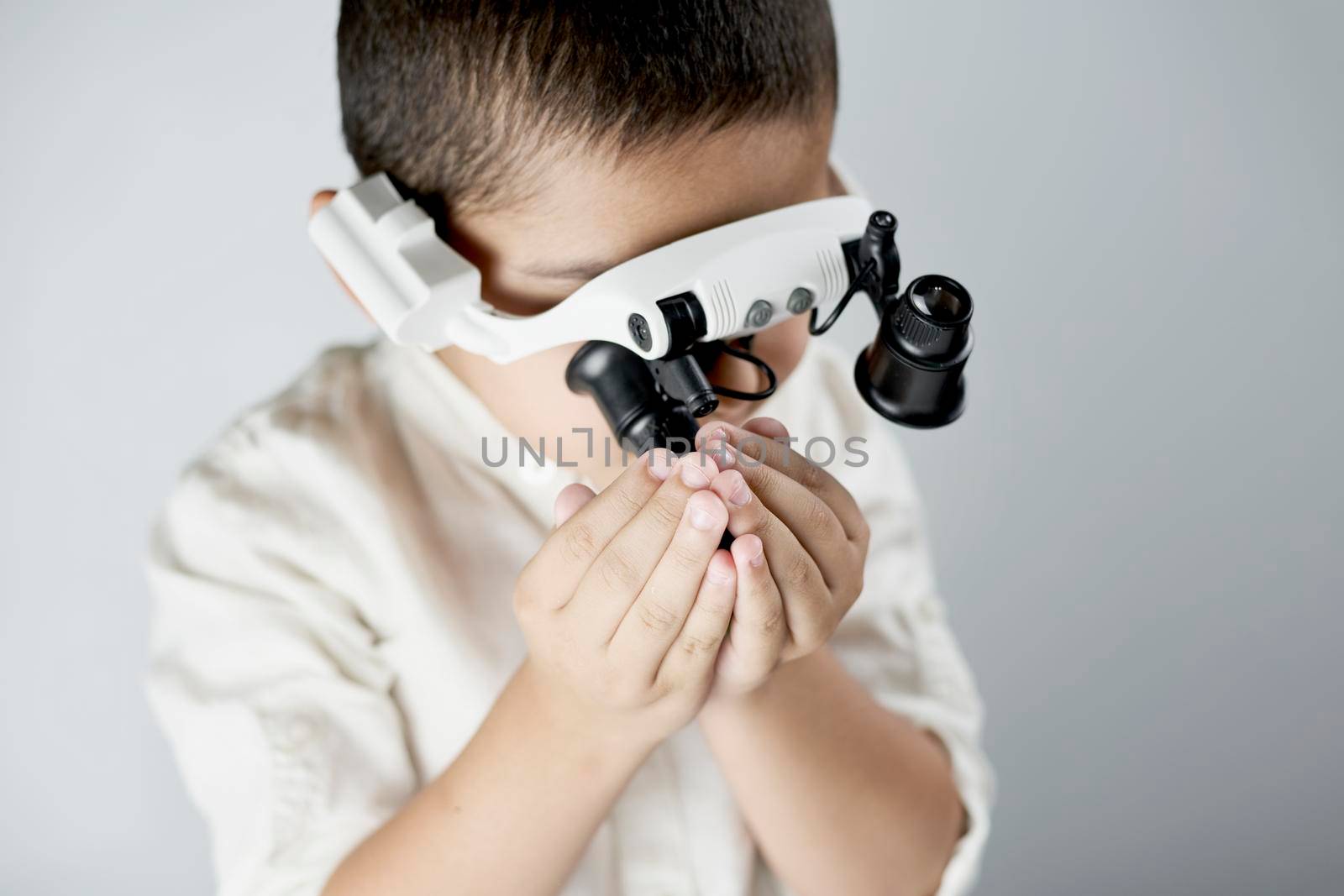 Schoolboy equipped with headband magnifying glass conducting scientific experiments at the workshop