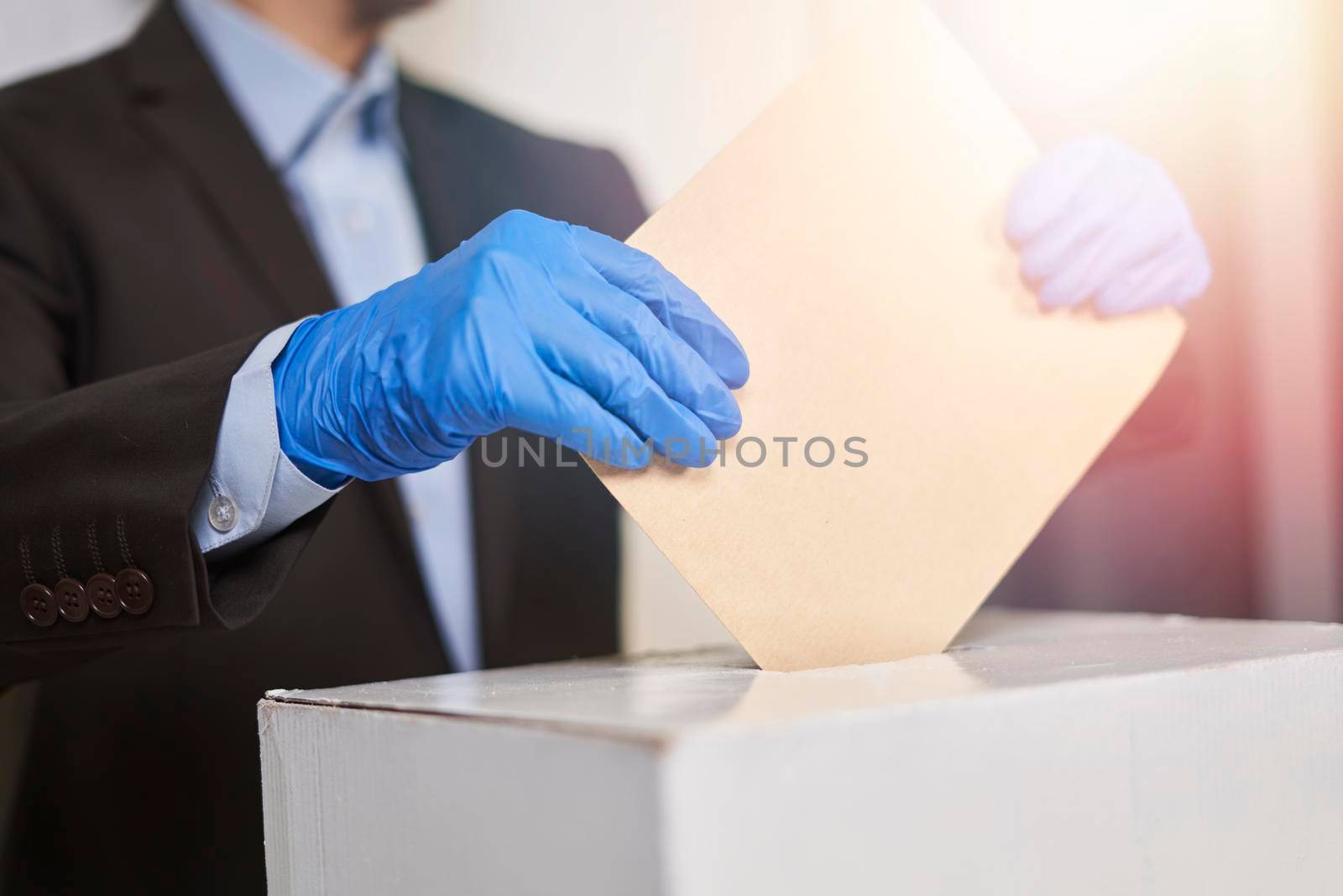 A person in medical gloves voting. Election concept. Presidential or Parliament election. A voter putting an election ballot into the box. Election during COVID-19 pandemic