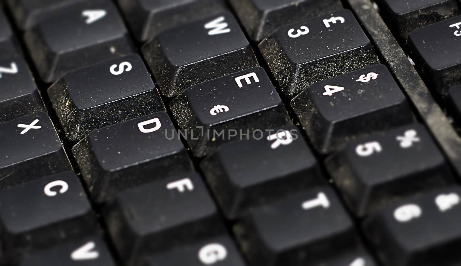 Detail of the buttons of a dusty black plastic european computer keyboard. by rarrarorro