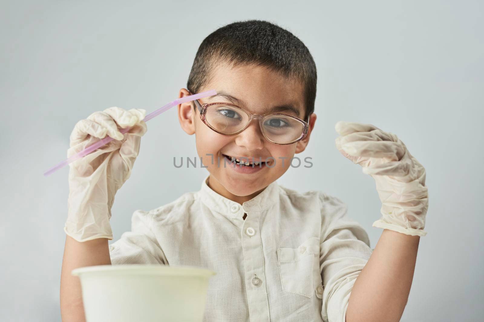 Funny nerd kid in glasses making experiments at the workshop and exploring the world of chemistry