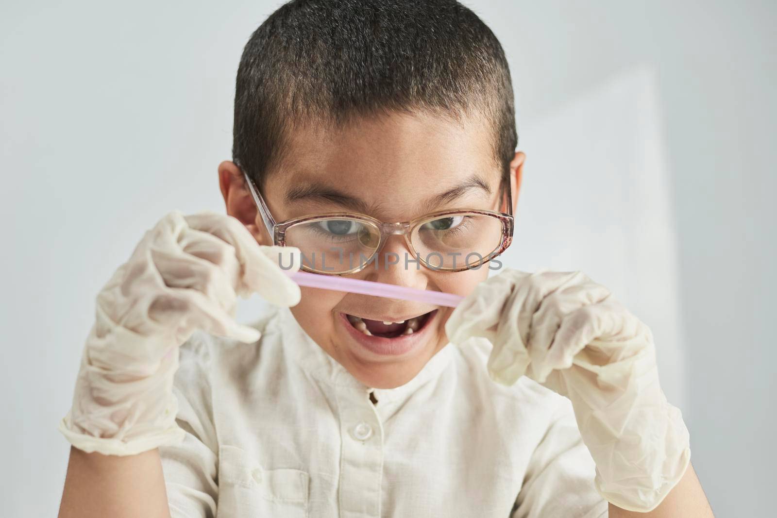 Portrait of 7 years old boy in glasses making funny facial expression against the white background
