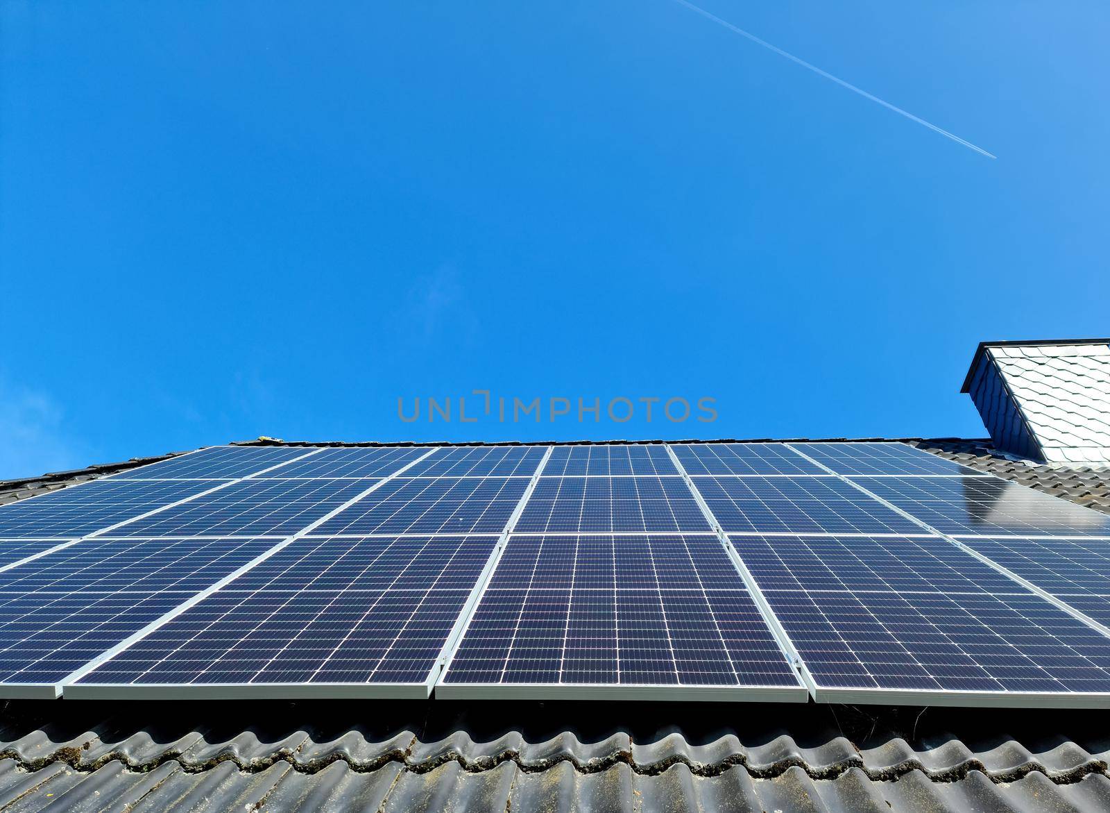 Solar panels producing clean energy on a roof of a residential house with black roof tiles