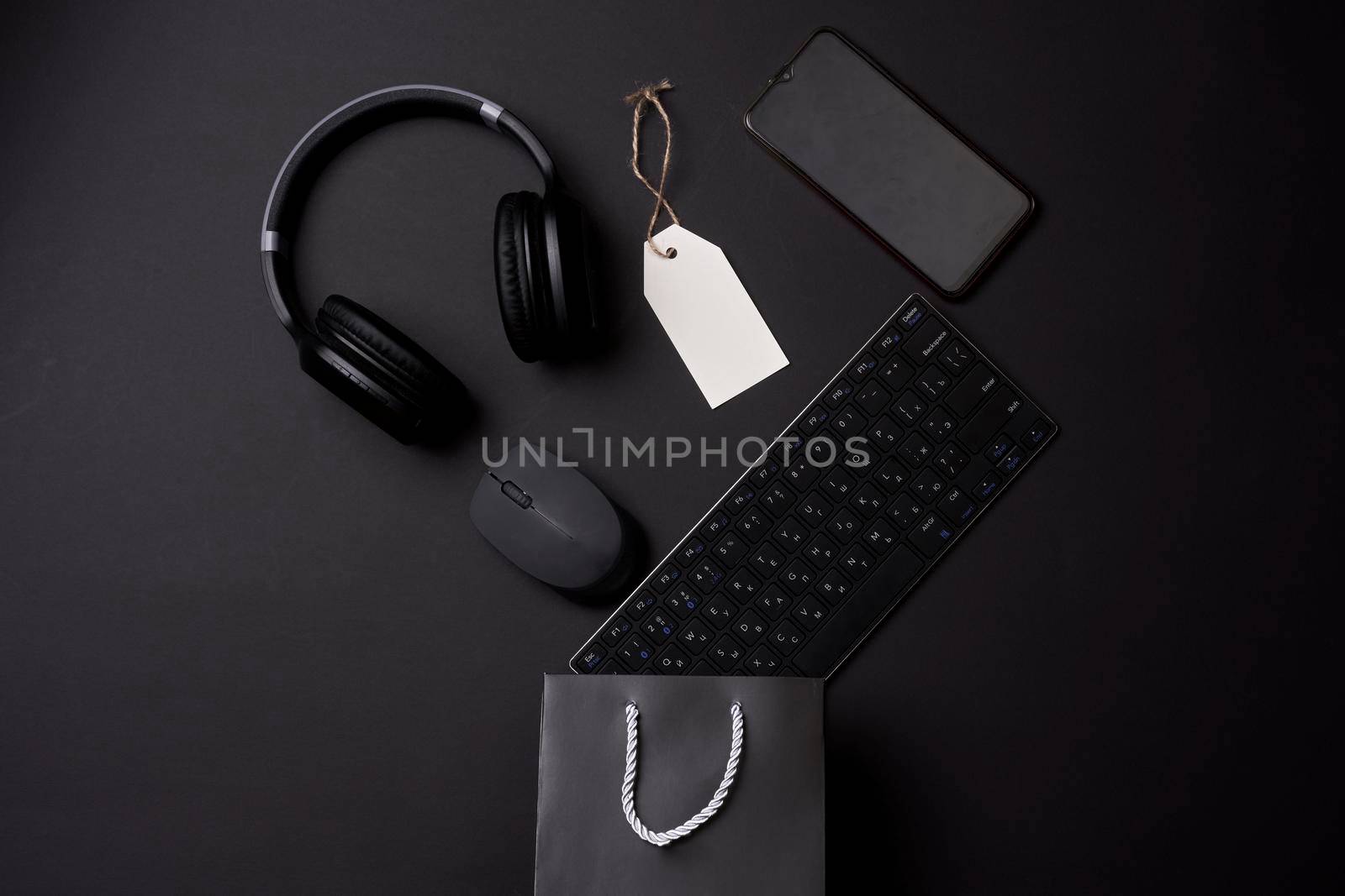 Black friday concept. A shopping bag with computer keyboard, mouse, headphones and mobile phone