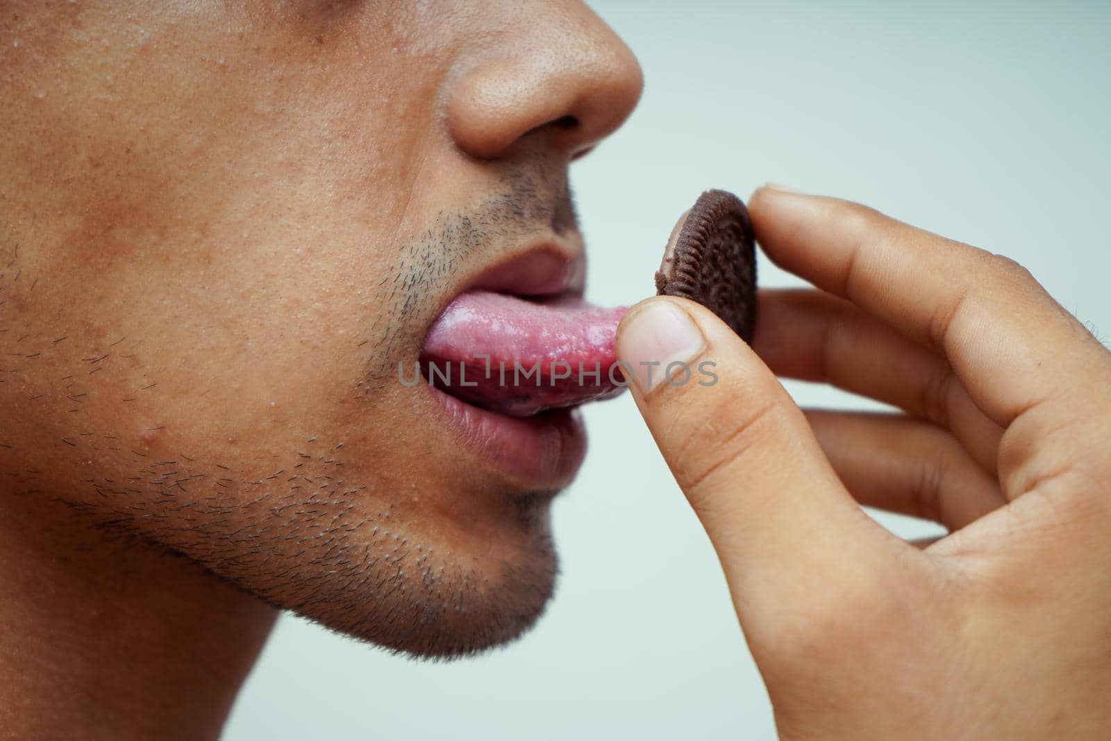 close up of a man licking chocolate biscuits