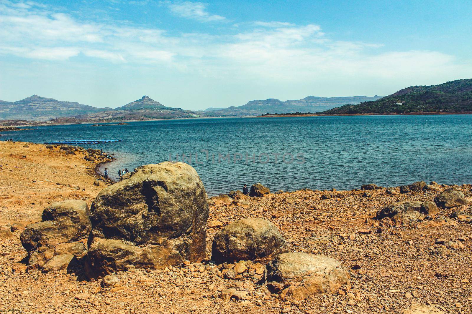 landscape of a lake from its rocky shore with mountains in the background