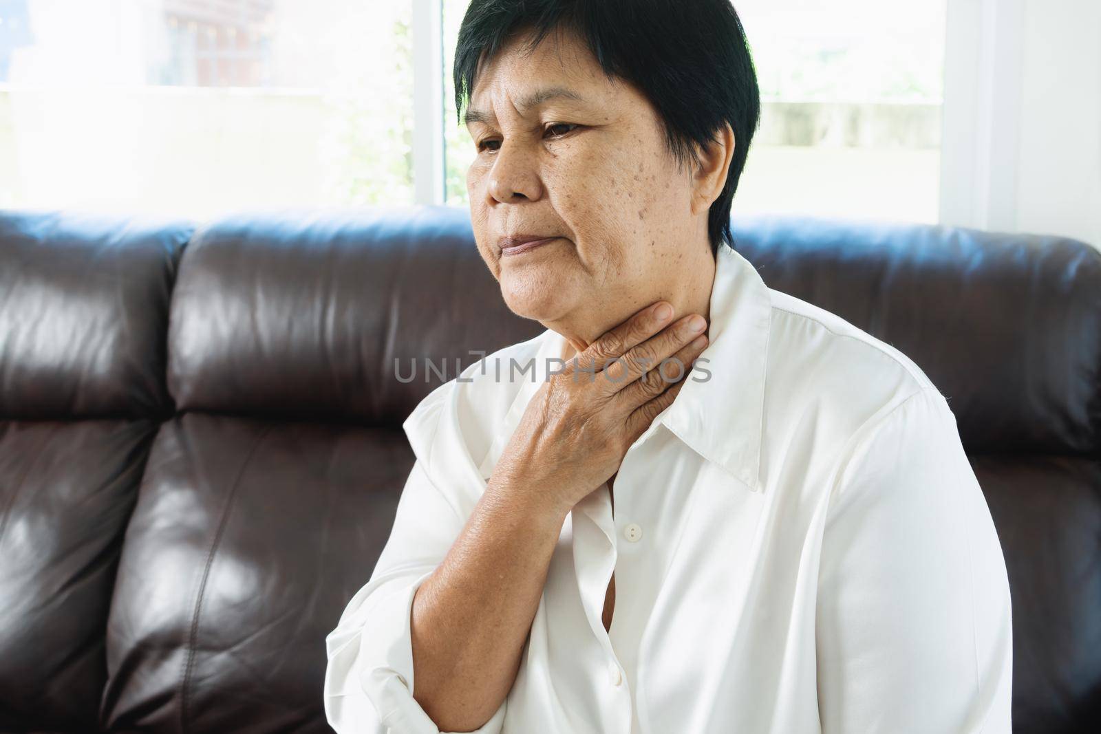 Senior adult women touching the neck feeling unwell coughing with sore throat pain.Healthcare and medicine concept by psodaz