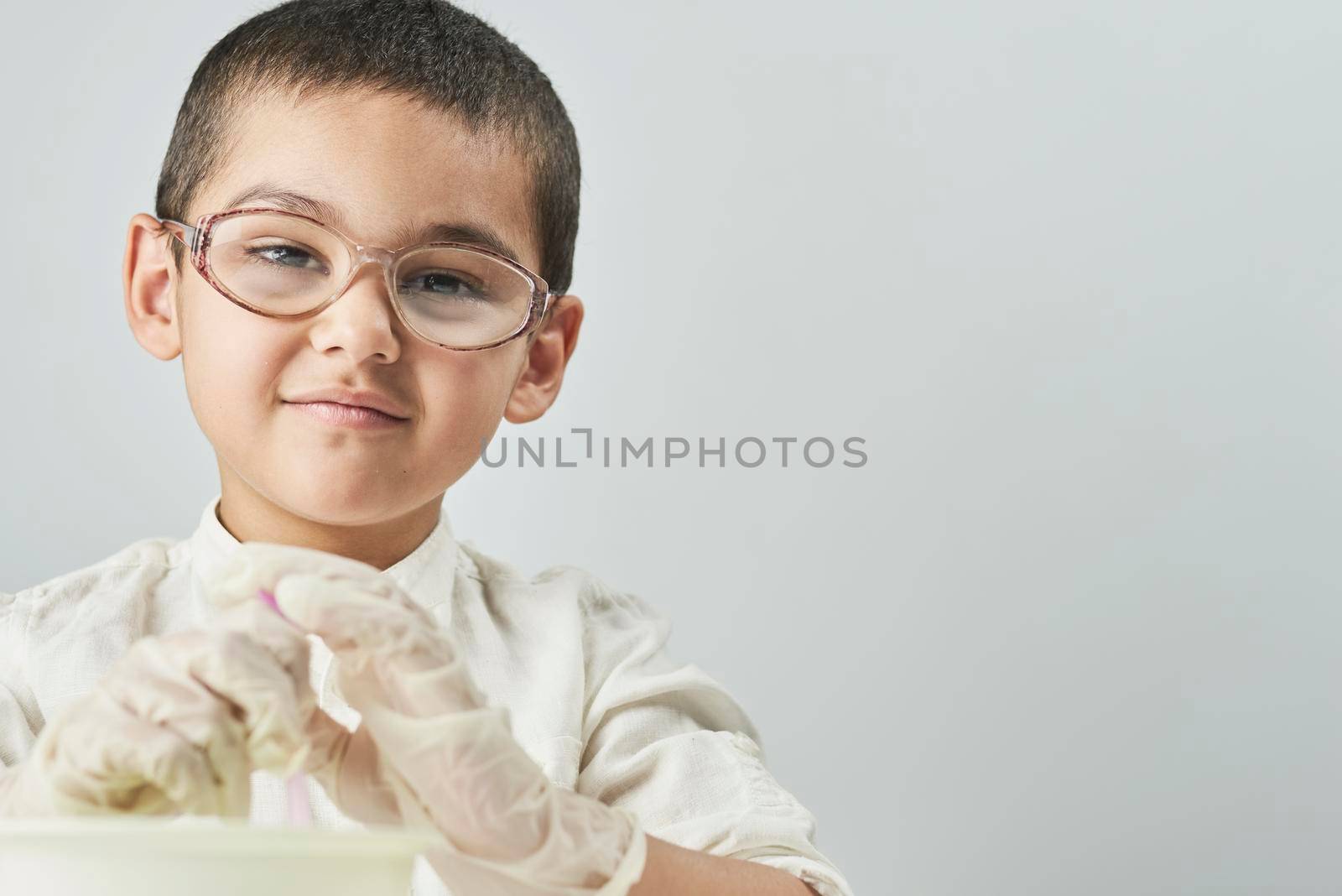 Portrait of 7 years old cute kid in glasses looking at camera against the white background