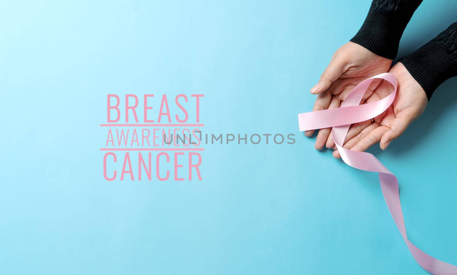 pink badge ribbon on woman hand to support breast cancer cause. breast cancer awareness concept by psodaz