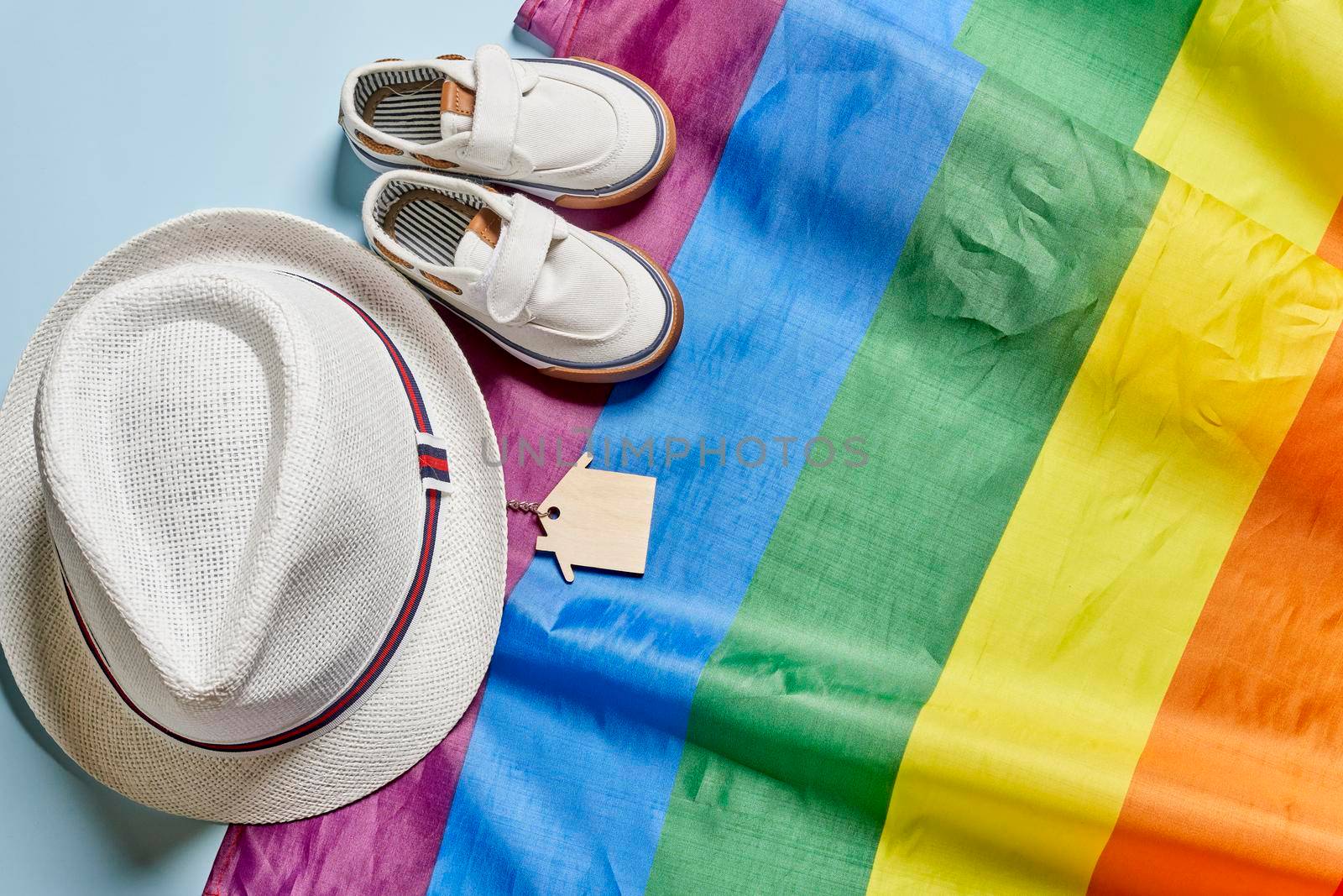 Travel hat, summer shoes and home keys on LBGTQ rainbow flag