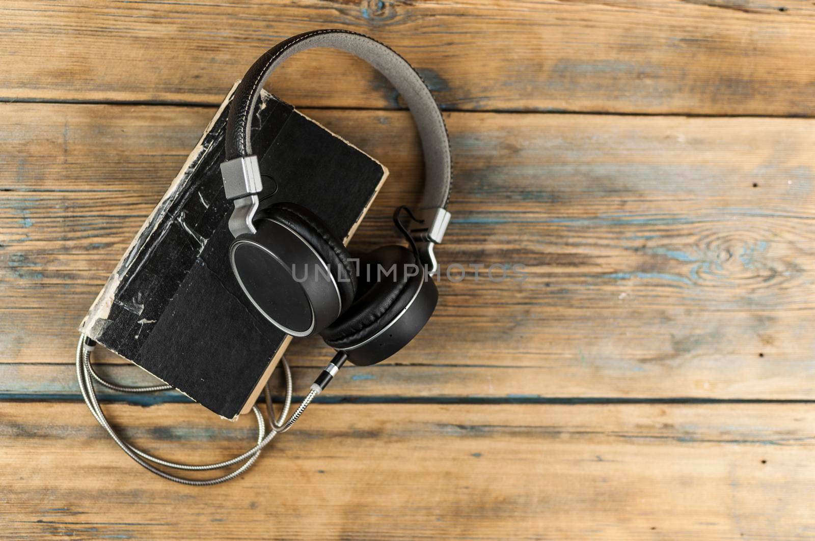 Audio book concept. Headphones and old book over wooden table. Top view with space for your text by inxti